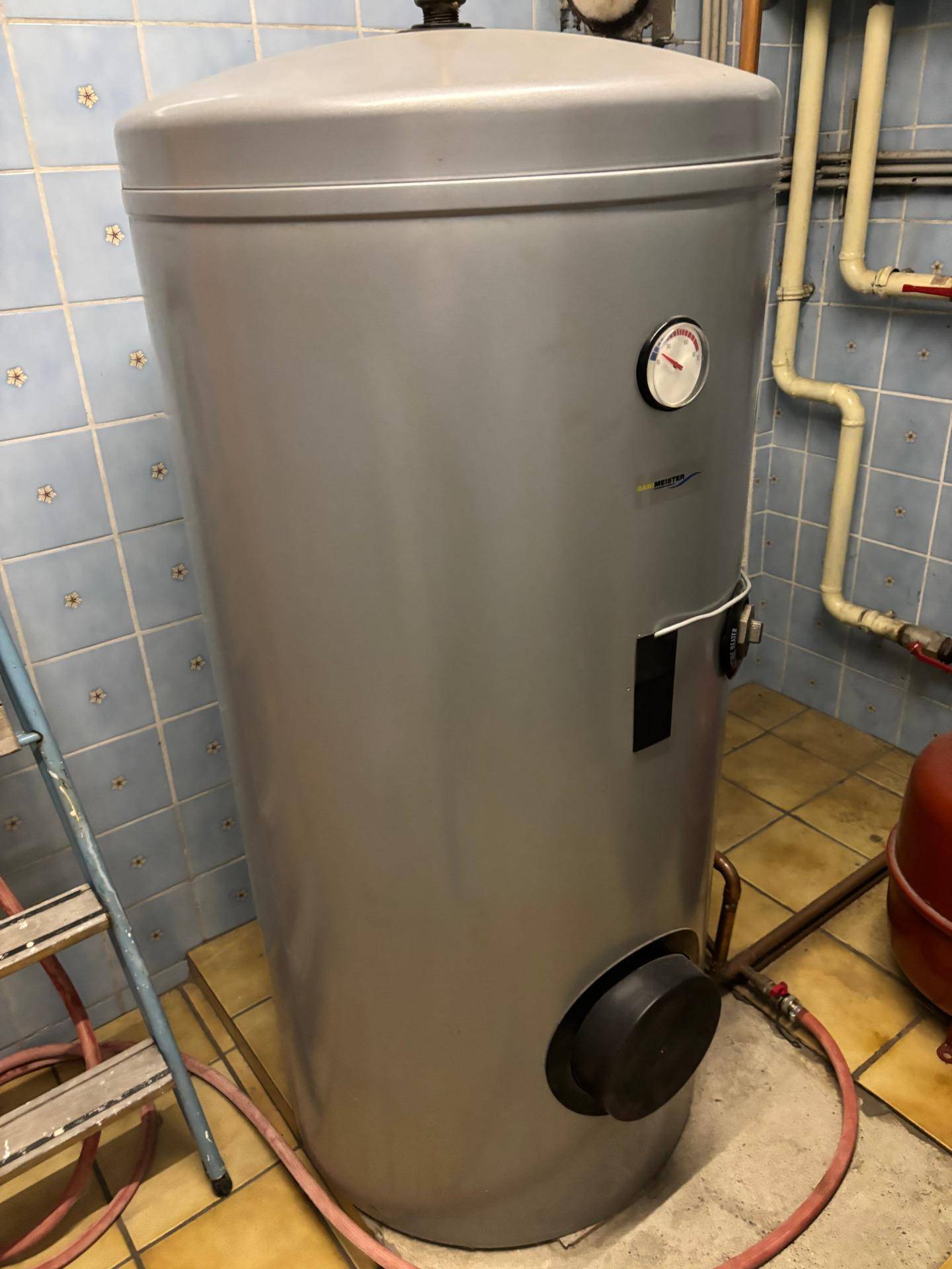 Hauswirtschaftsraum mit einem großen Warmwasserspeicher und blauen Fliesen an den Wänden.