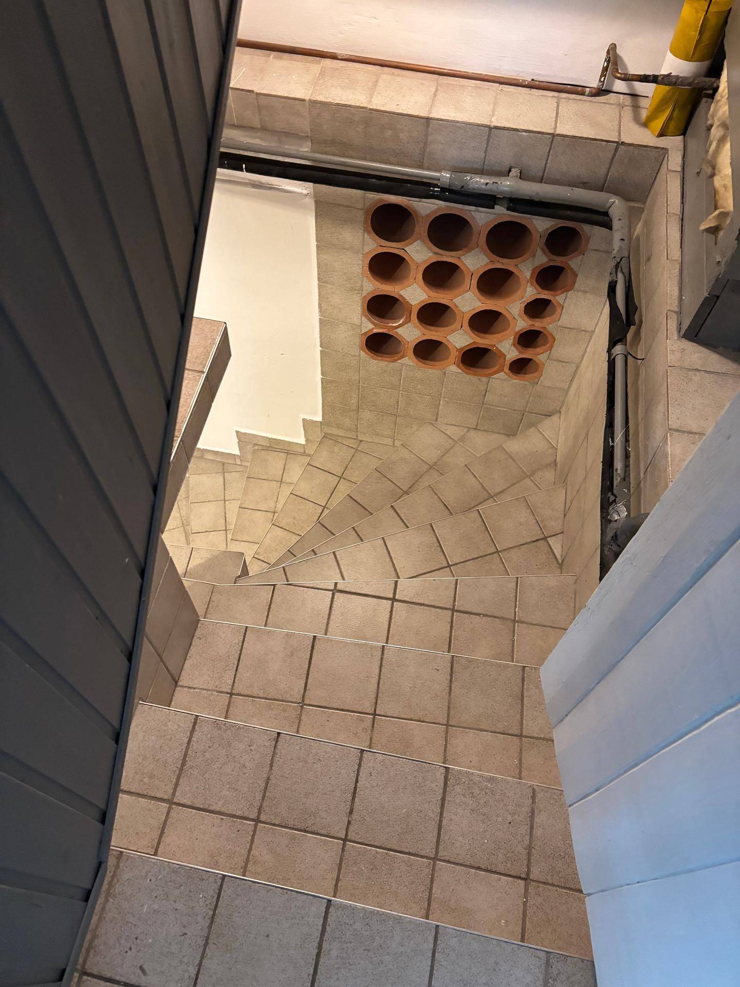 Gefliestes Treppenhaus, das in den Keller führt, mit einer integrierten Weinlagerung an der Decke.