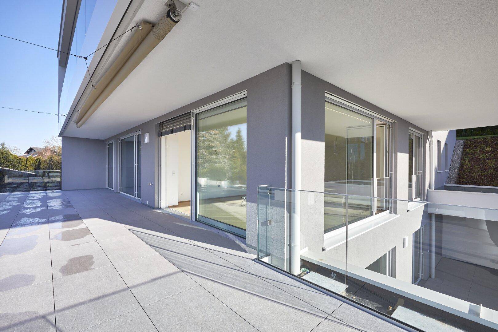 Moderne Architektur mit großer Terrasse, Glasgeländer und weitem Blick.