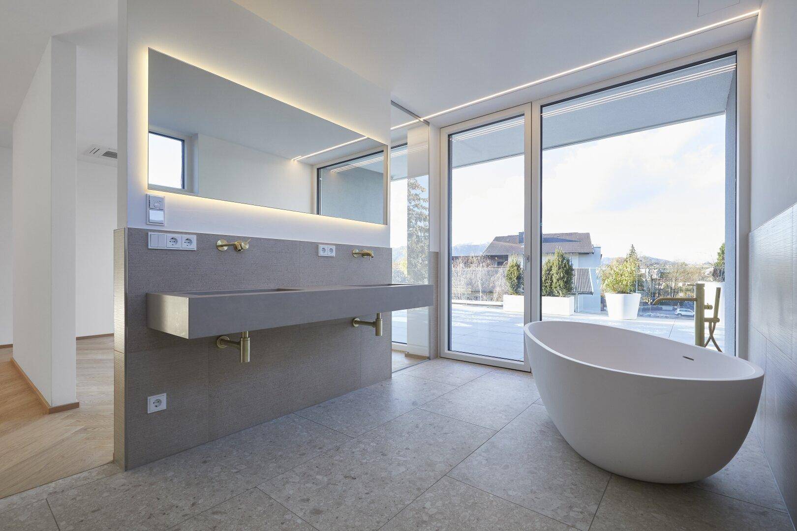 Luxuriöses Badezimmer mit freistehender Badewanne, Doppelwaschbecken und Terrassenzugang.