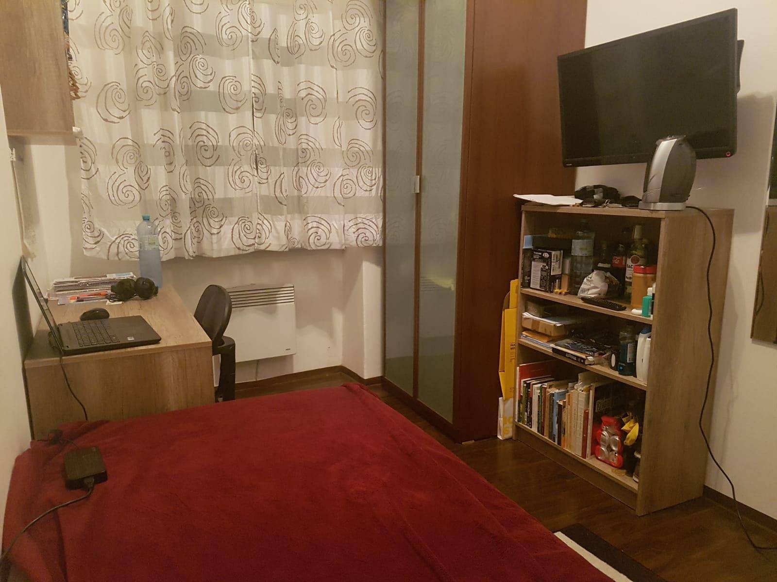 Gemütliches Schlafzimmer mit Bett, Schreibtisch, Kleiderschrank und Fernseher.