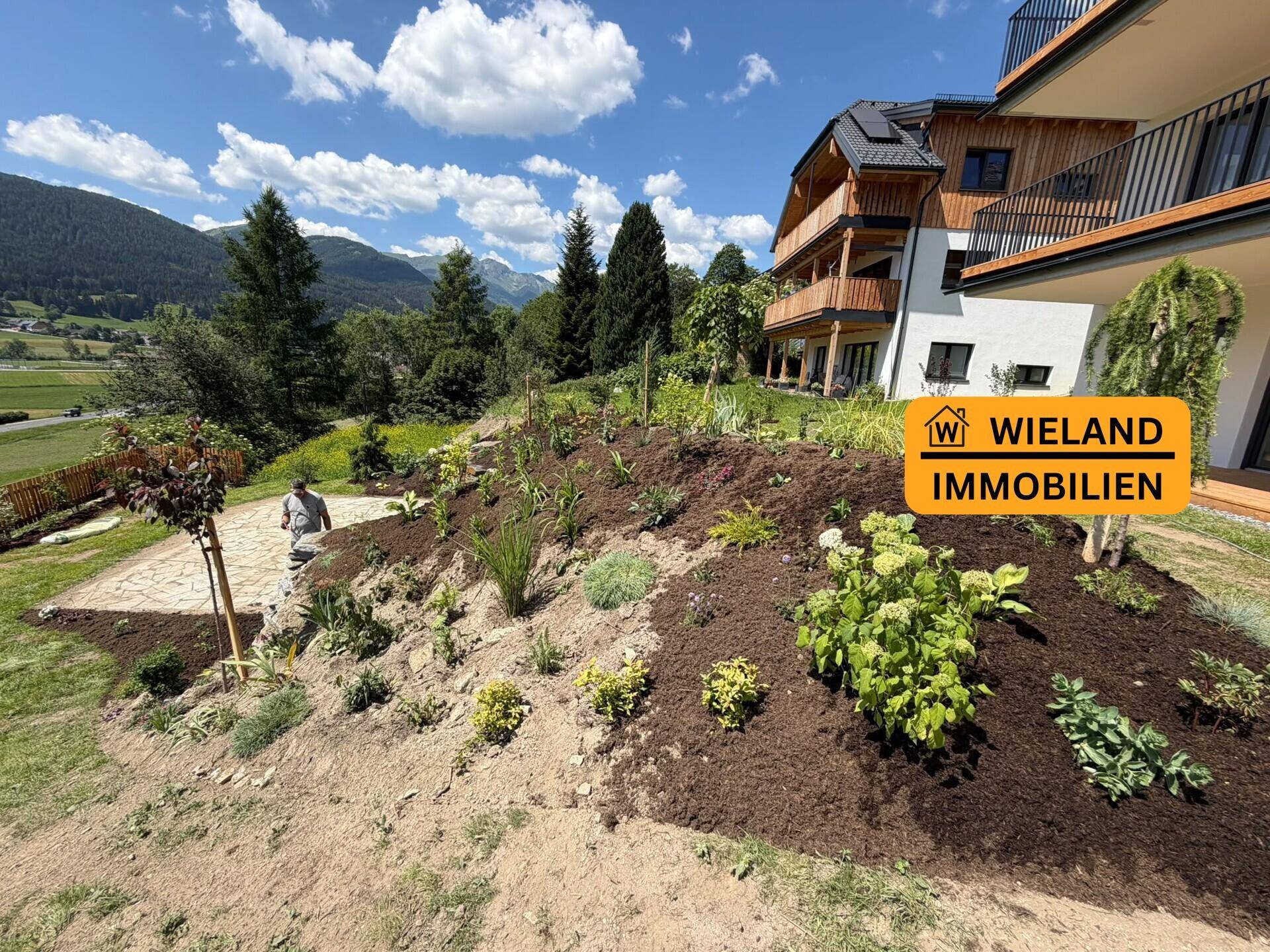 Gepflegter Gartenbereich mit Blick auf die Berge und die moderne Wohnanlage.