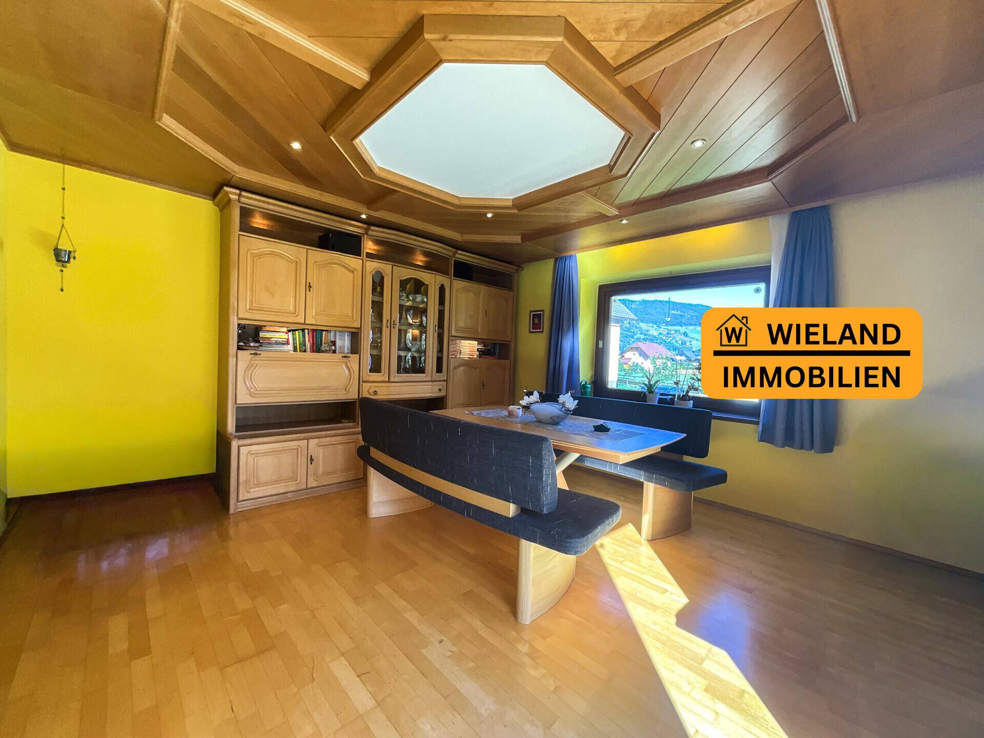 Gemütlicher Essbereich mit Holztäfelung an Decke und Wänden sowie Einbauschränken und Blick ins Grüne.