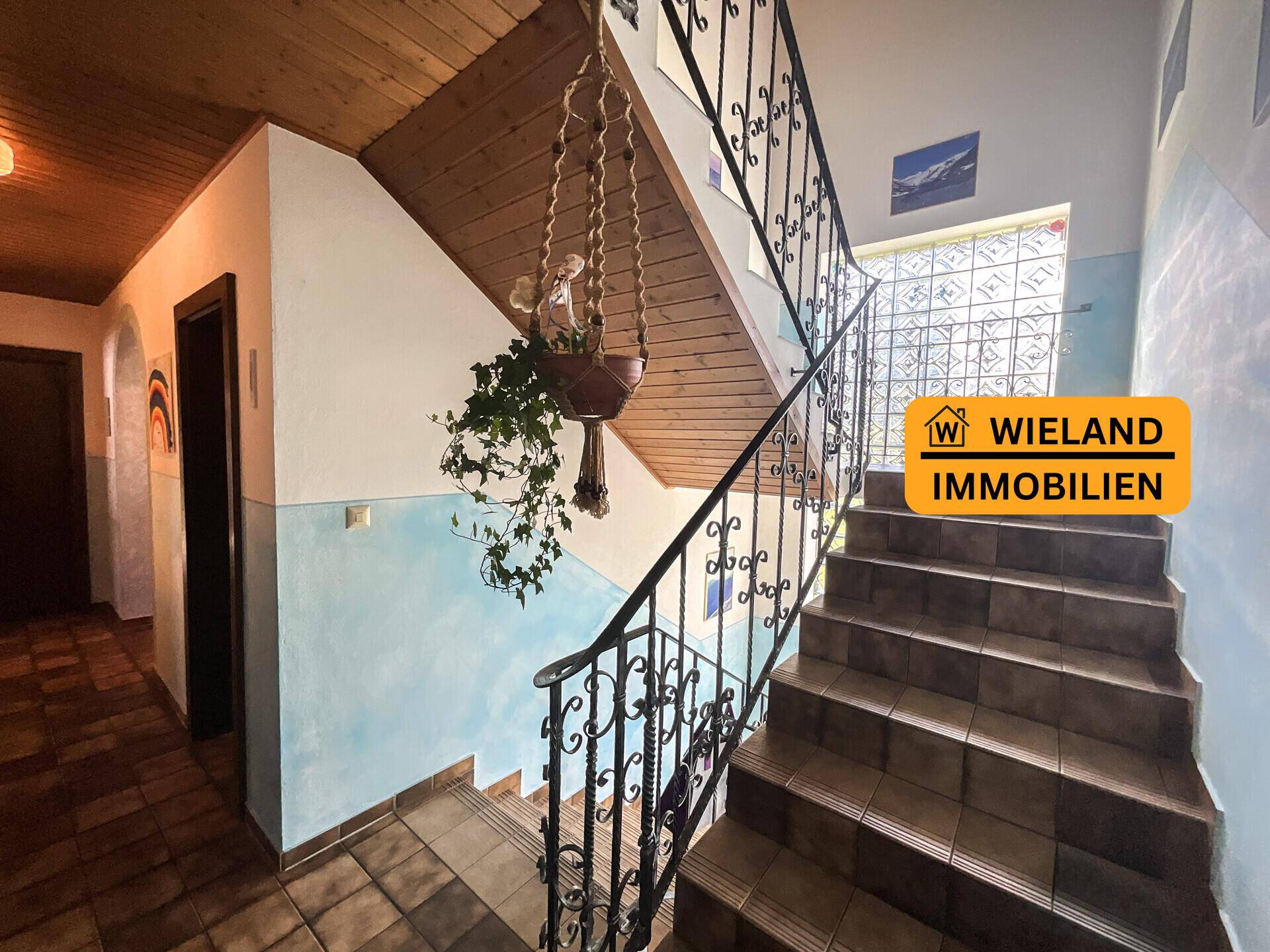 Treppenhaus mit schmiedeeisernem Geländer und Fliesenboden, führt in die oberen Etagen.