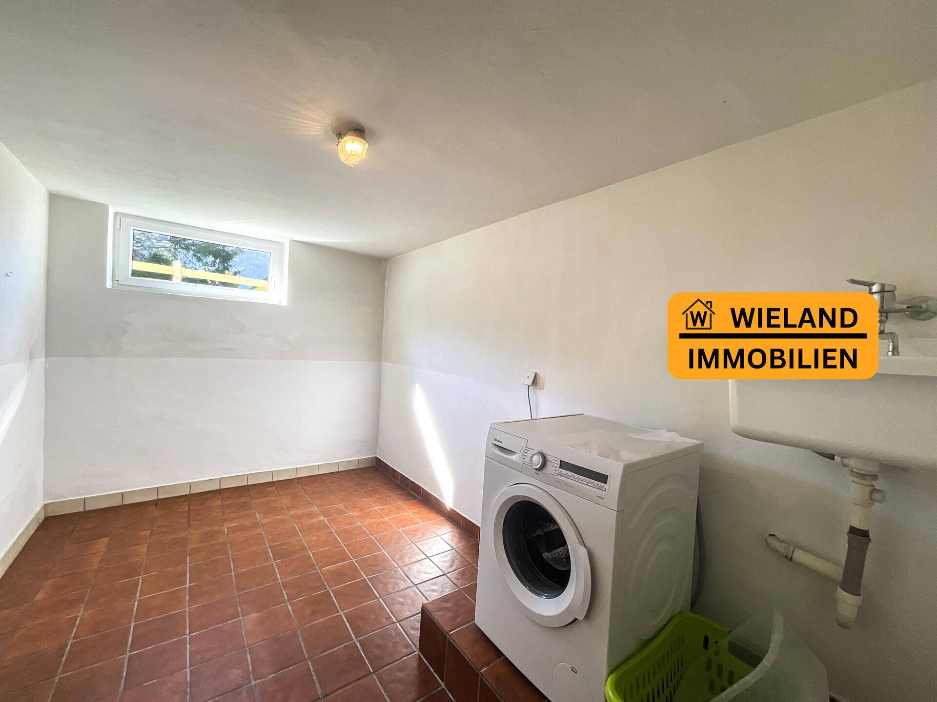 Waschküche im Keller mit Waschmaschine und Waschbecken, bietet praktischen Arbeitsbereich.