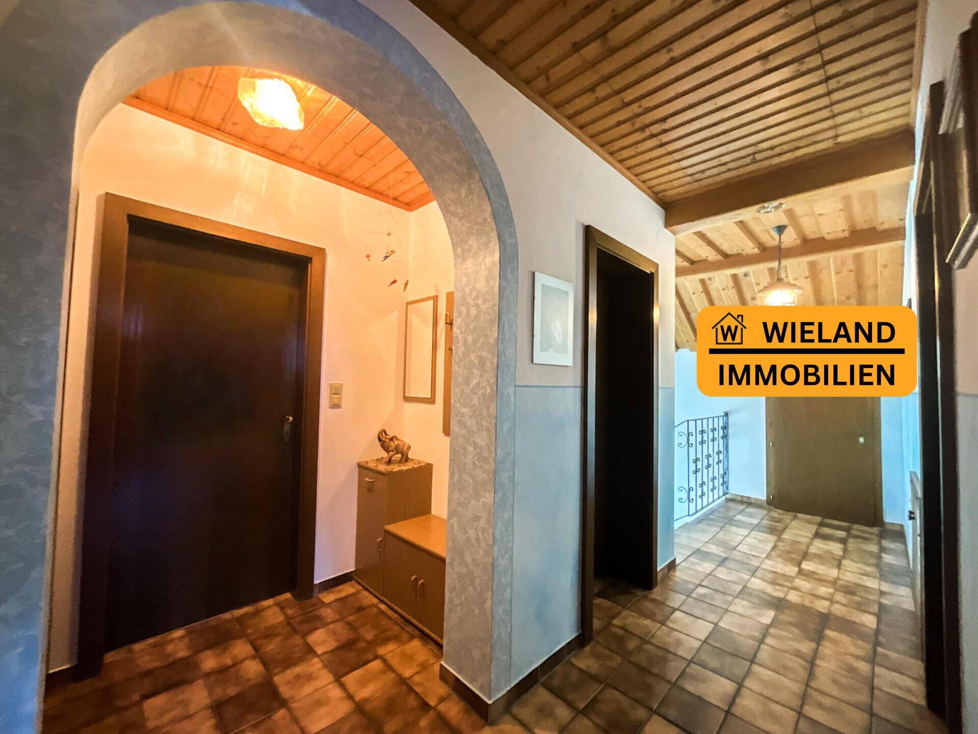 Geräumiger Flur mit Fliesenboden und Holzdecke, verbindet verschiedene Räume.