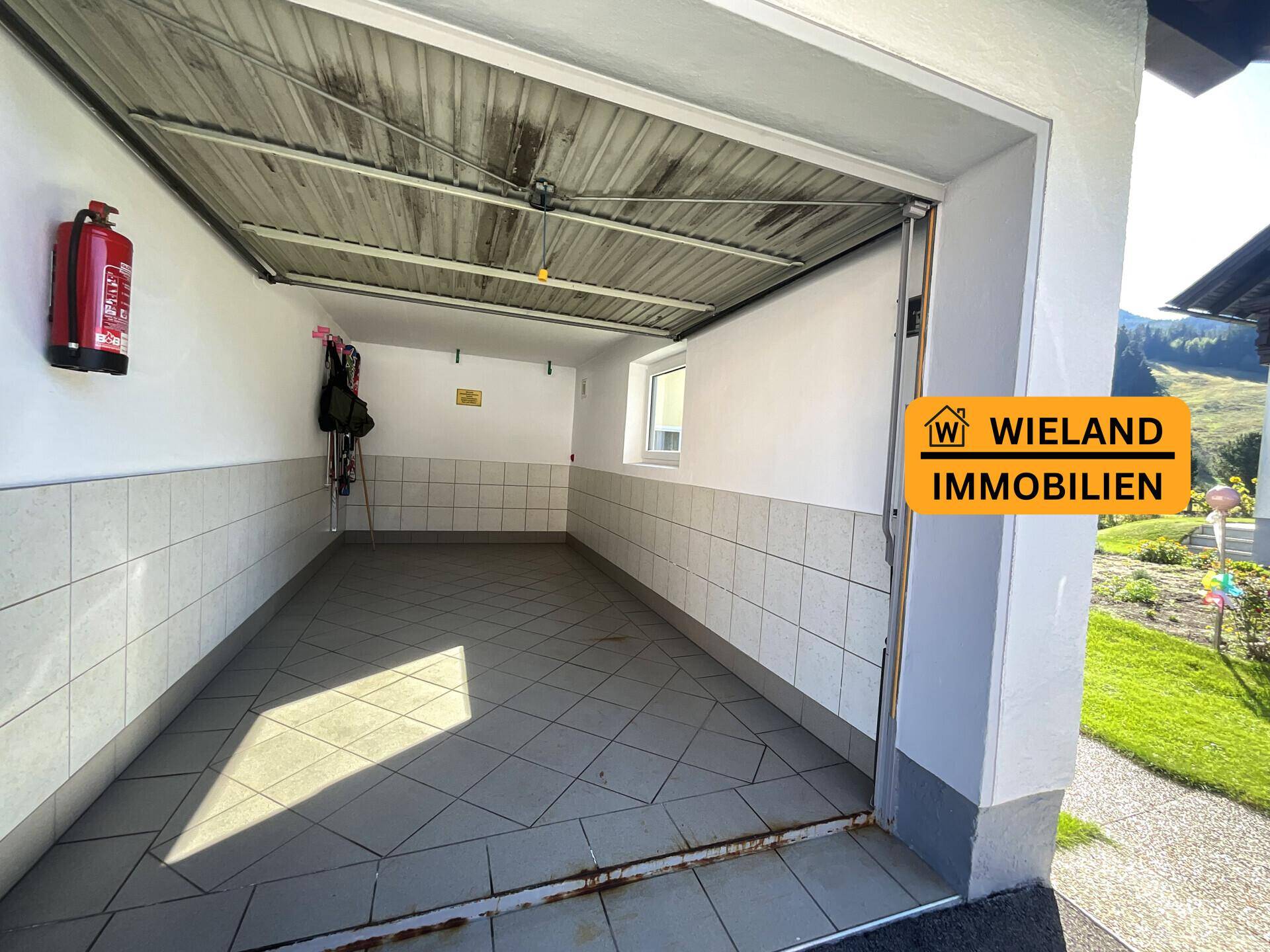 Geräumige Garage mit Fliesenboden und Rolltor, bietet Platz für ein Fahrzeug.
