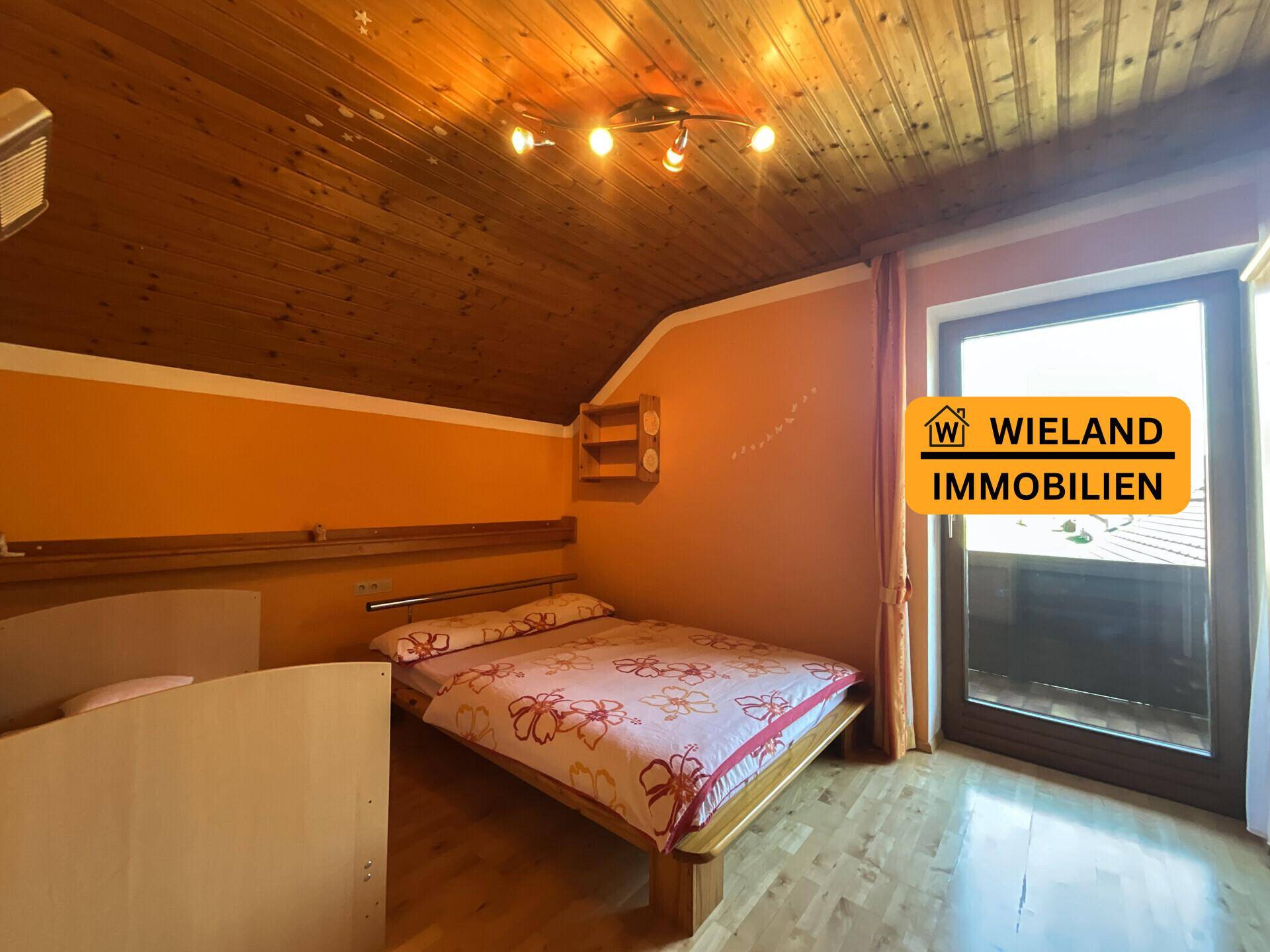Kinderzimmer mit Holzboden, orangefarbenen Wänden und Balkonzugang, gemütlich eingerichtet.