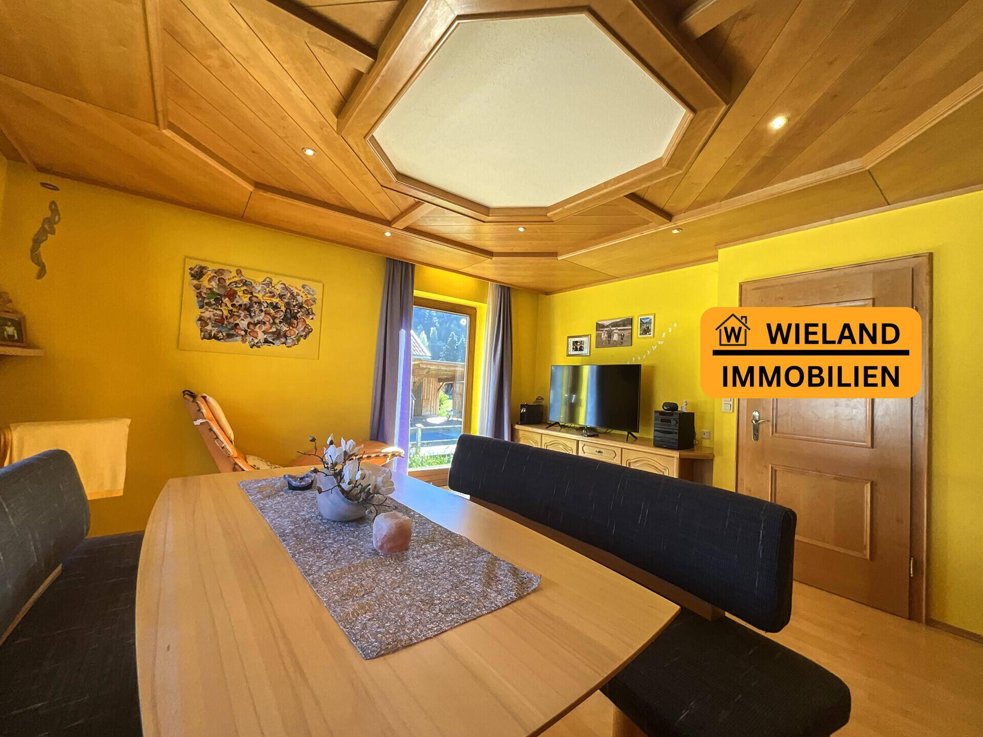 Gemütlicher Essbereich mit Holztäfelung an Decke und Wänden, gelben Wänden und Bergblick.