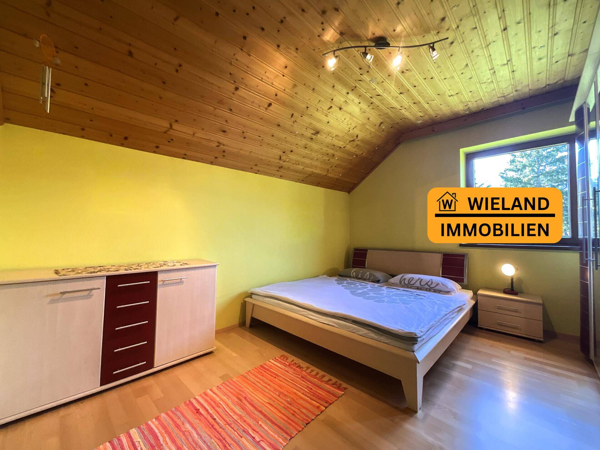Schlafzimmer mit Holzboden, gelben Wänden und schräger Holzdecke, bietet eine gemütliche Atmosphäre.