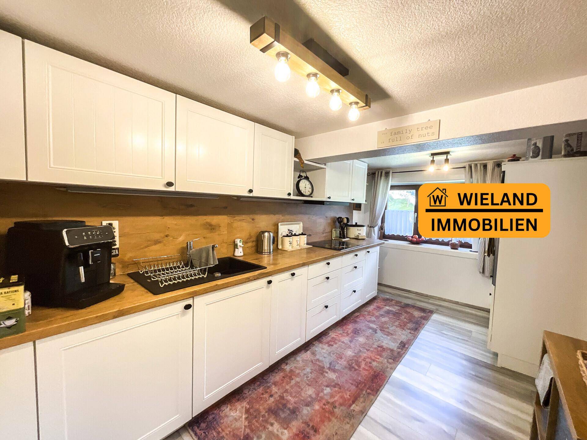 Helle Küche mit weißen Schränken, Holz-Arbeitsplatten und modernen Geräten, ideal für kulinarische Aktivitäten.