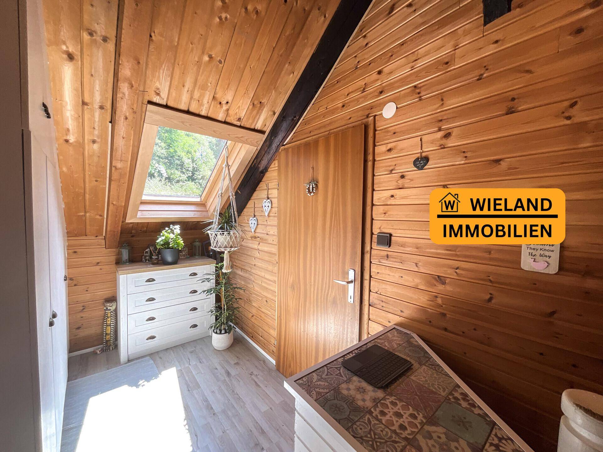 Heller Flurbereich mit Holztäfelung, Dachfenster und Kommode, die für zusätzlichen Stauraum sorgt.