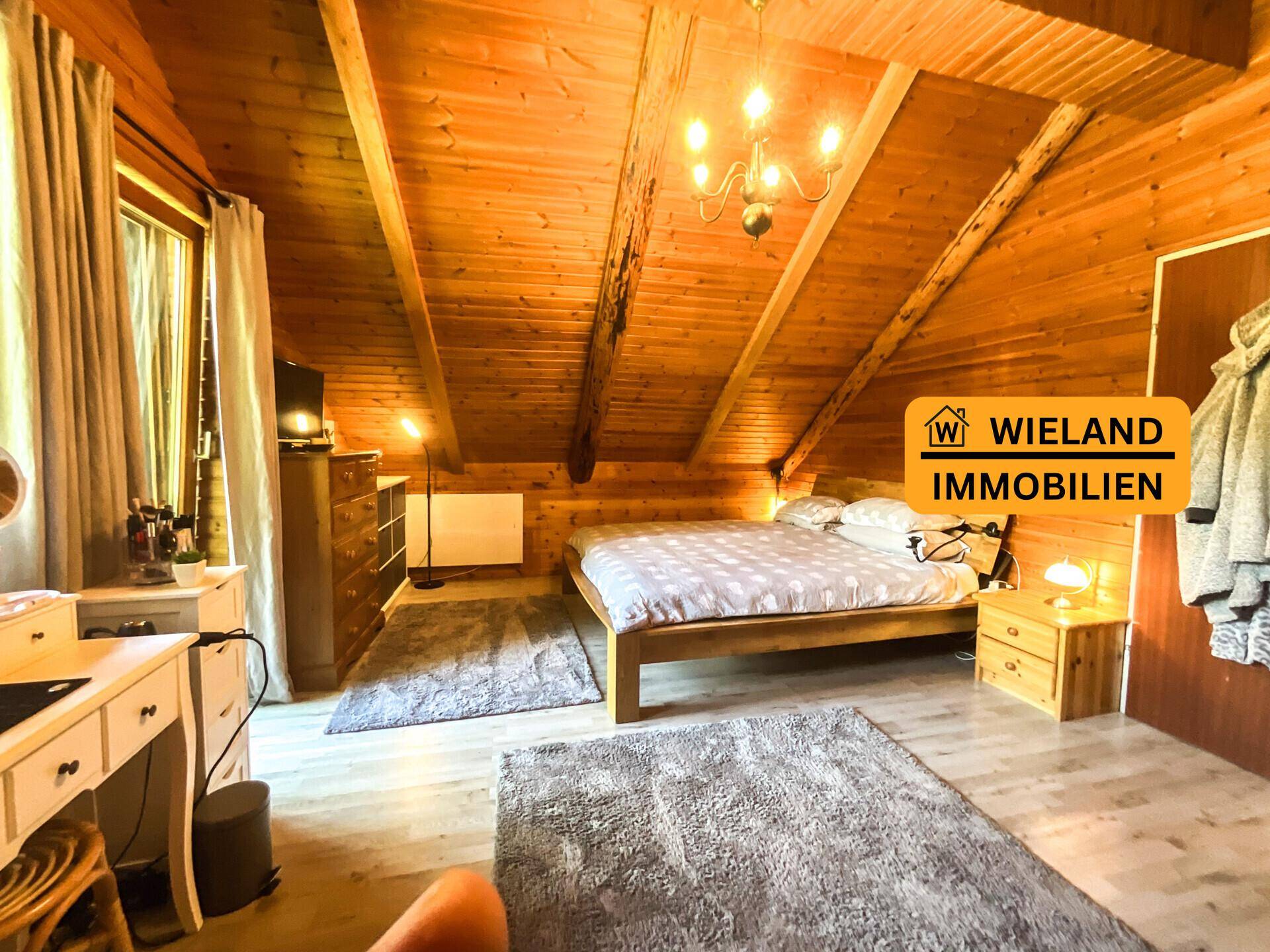 Gemütliches Schlafzimmer mit Holztäfelung, Dachschräge und Doppelbett, ausgestattet mit rustikalen Möbeln.