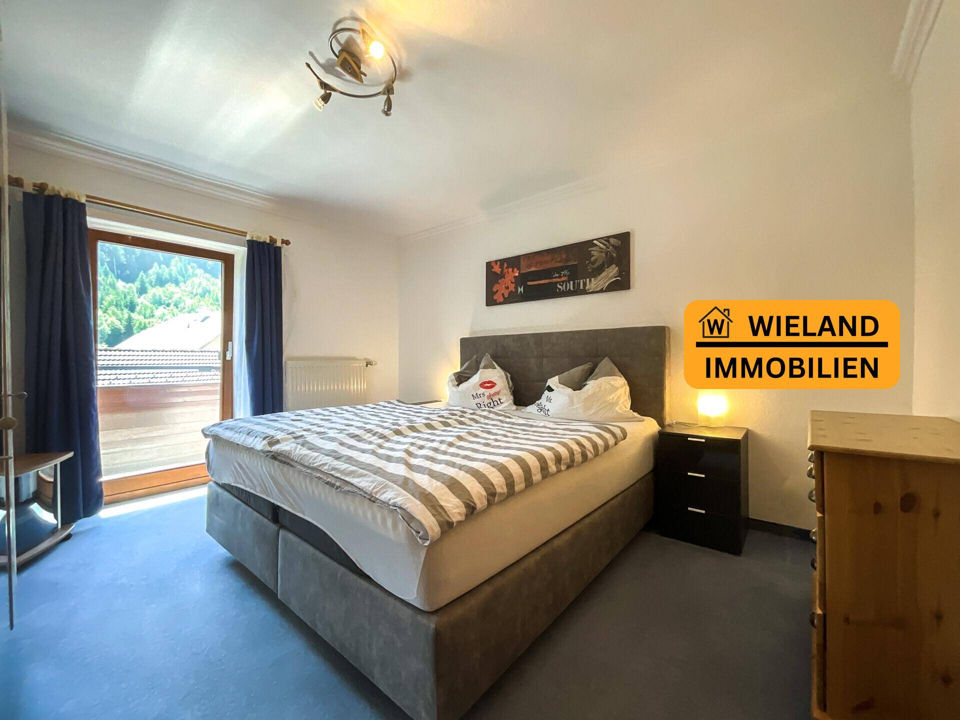 Schlafzimmer mit Doppelbett, Teppichboden und Zugang zu einem Balkon mit Bergblick.