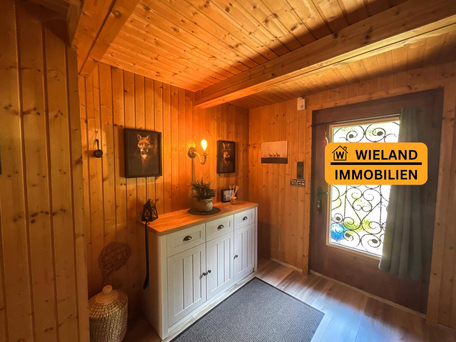 Eingangsbereich mit rustikaler Holztäfelung, Konsole und einer verzierten Haustür, die zum Charme beiträgt.