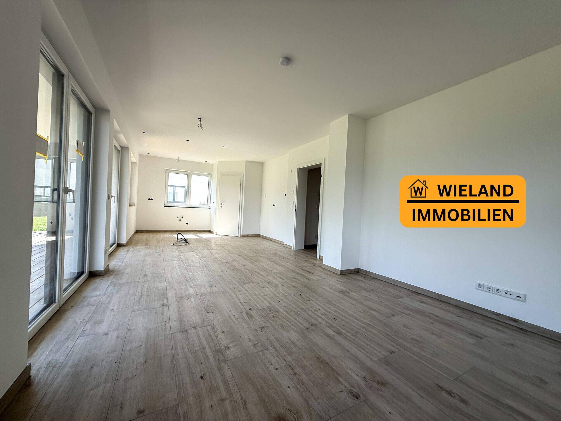 Lichtdurchfluteter Wohnraum mit modernem Bodenbelag und weitem Ausblick in die Landschaft.
