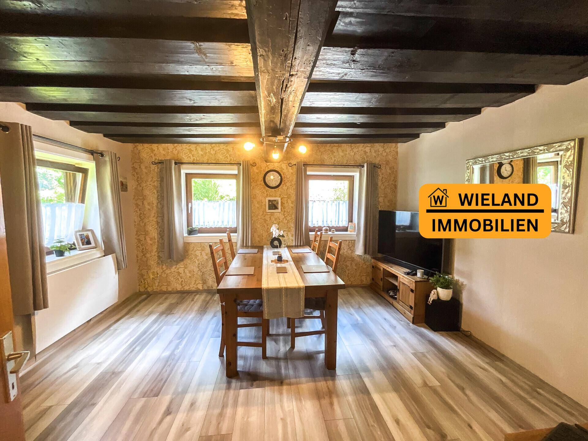 Esszimmer mit rustikalem Holztisch, dunklen Deckenbalken und strukturierten Wänden, ideal für gemeinsame Mahlzeiten.