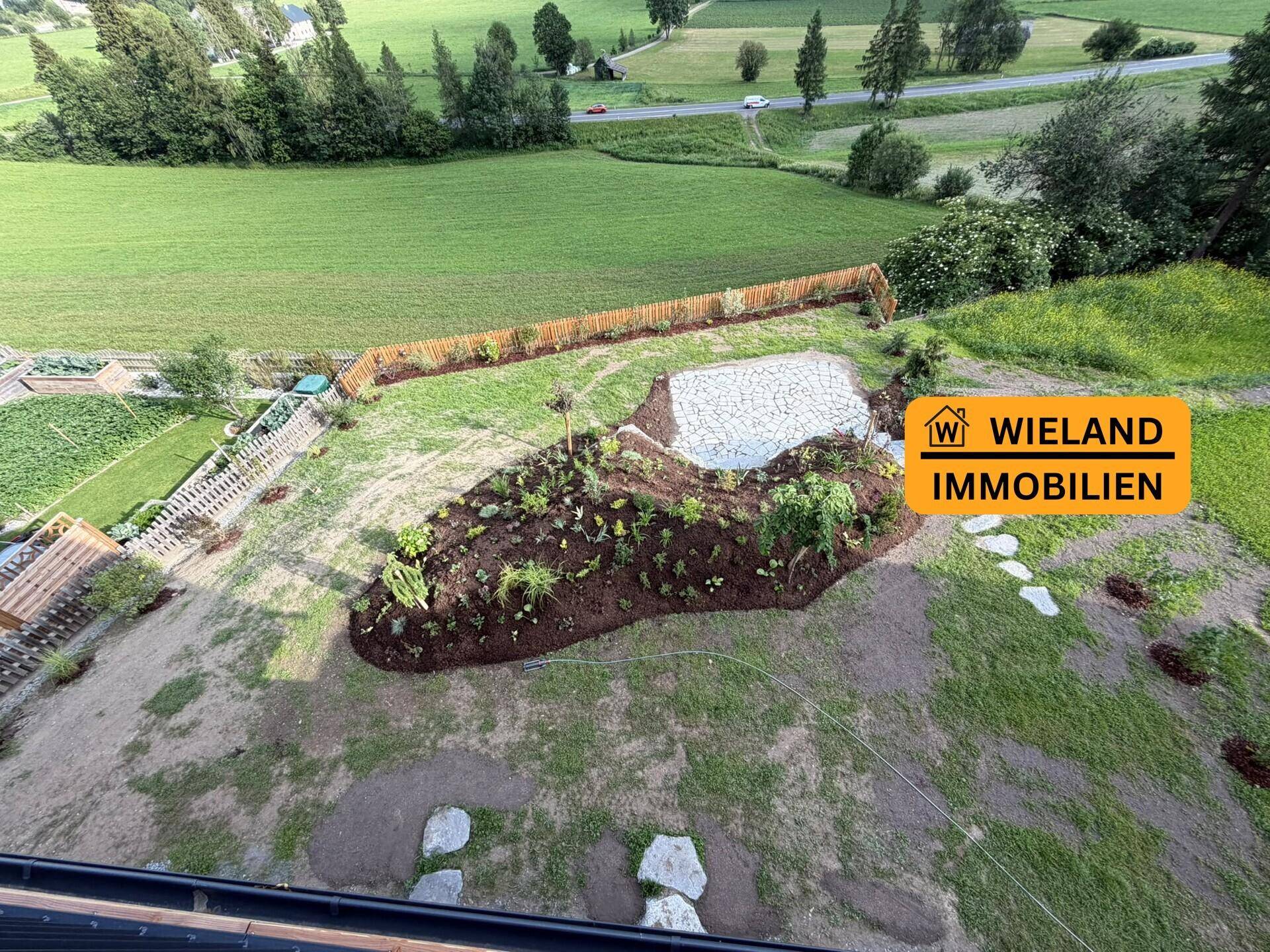 Vogelperspektive des weitläufigen Gartens mit Rasenflächen, neuen Beeten und Fernblick.