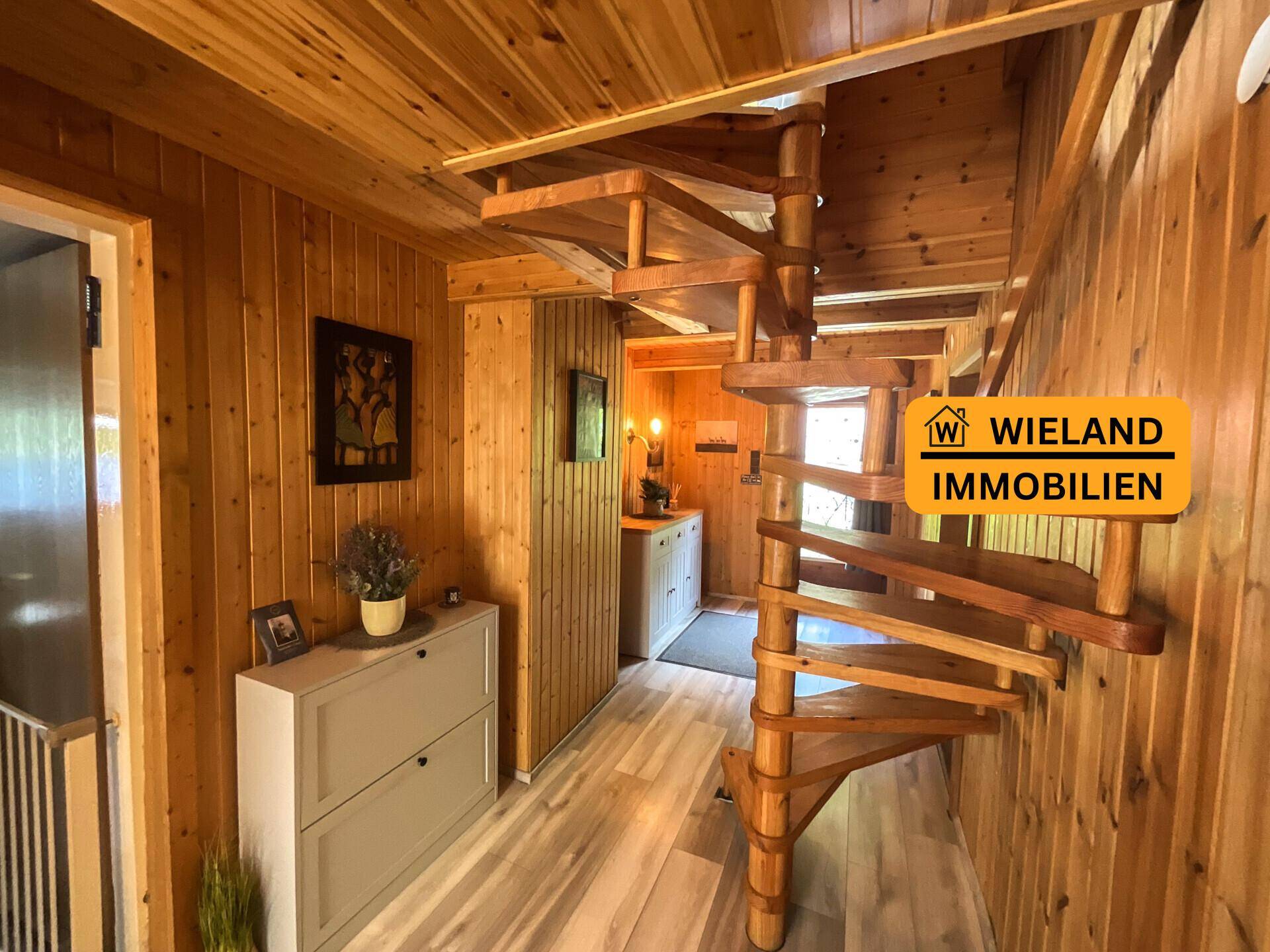 Flur mit Holztäfelung und einer eleganten Holz-Wendeltreppe, die die verschiedenen Ebenen verbindet.