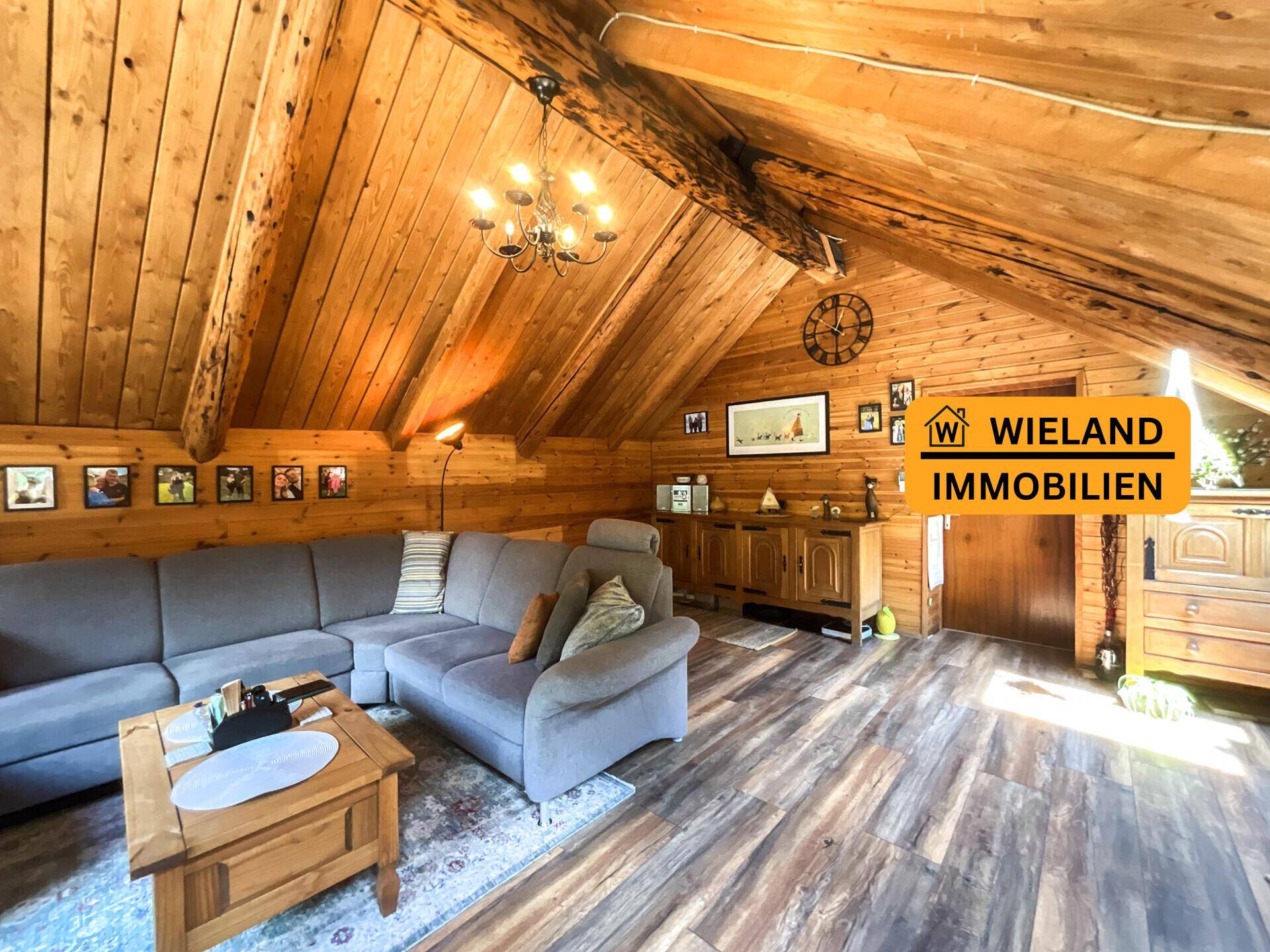 Geräumiges Wohnzimmer mit rustikaler Holztäfelung, sichtbaren Balken und bequemer Sitzecke.