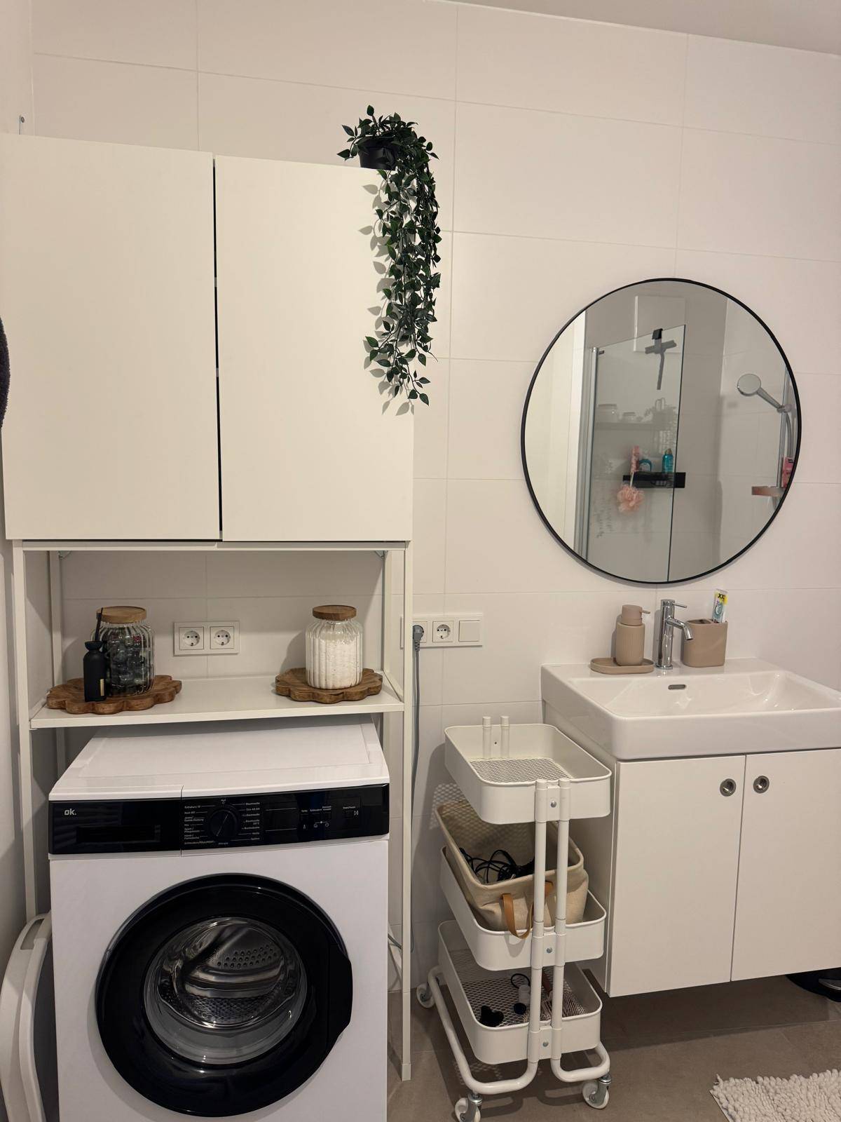 Modernes Badezimmer mit Waschmaschine, Spiegelschrank und weißen Fliesen.