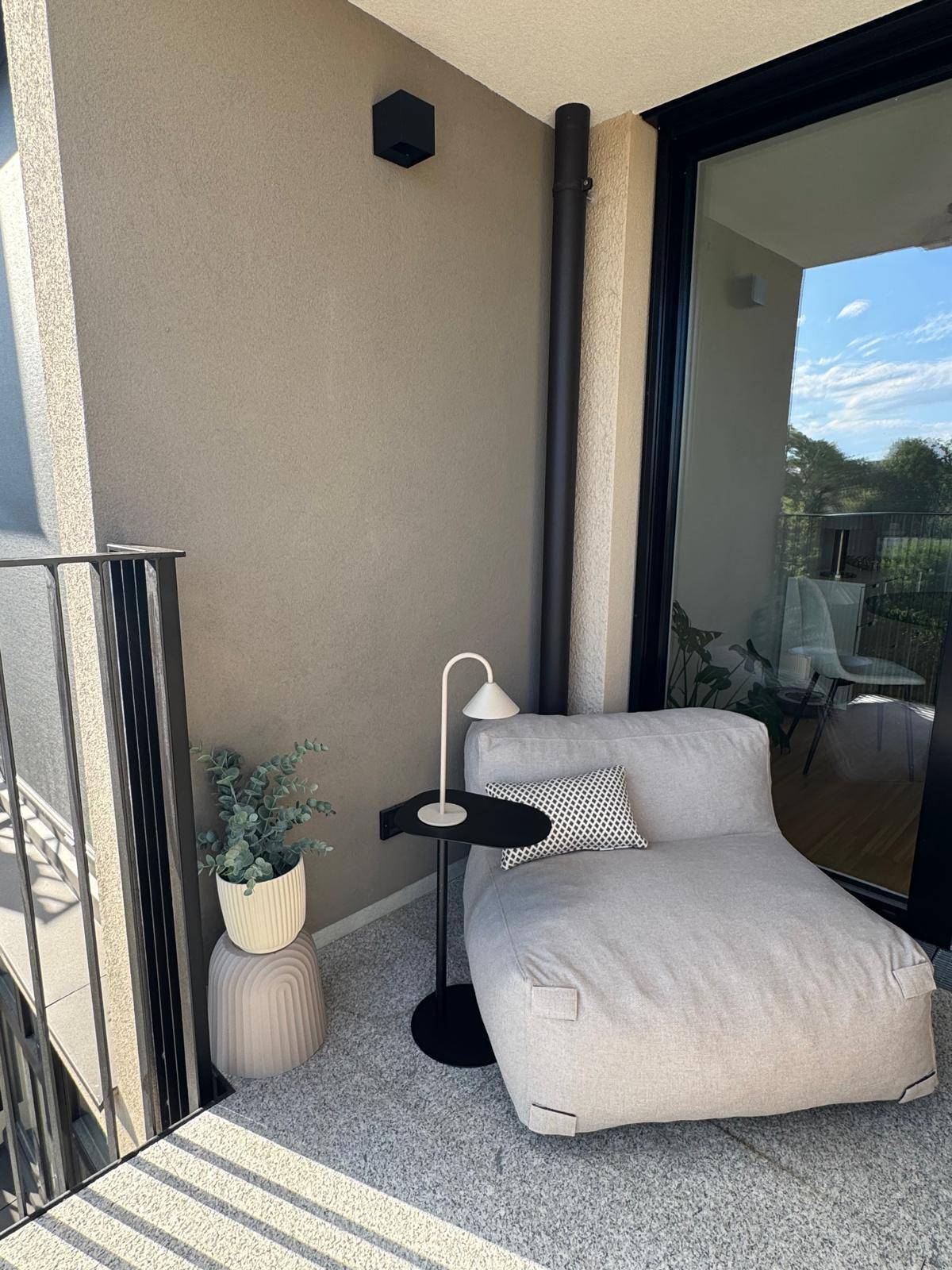 Gemütlicher Balkon mit Sitzgelegenheit und Blick ins Grüne an einem sonnigen Tag.