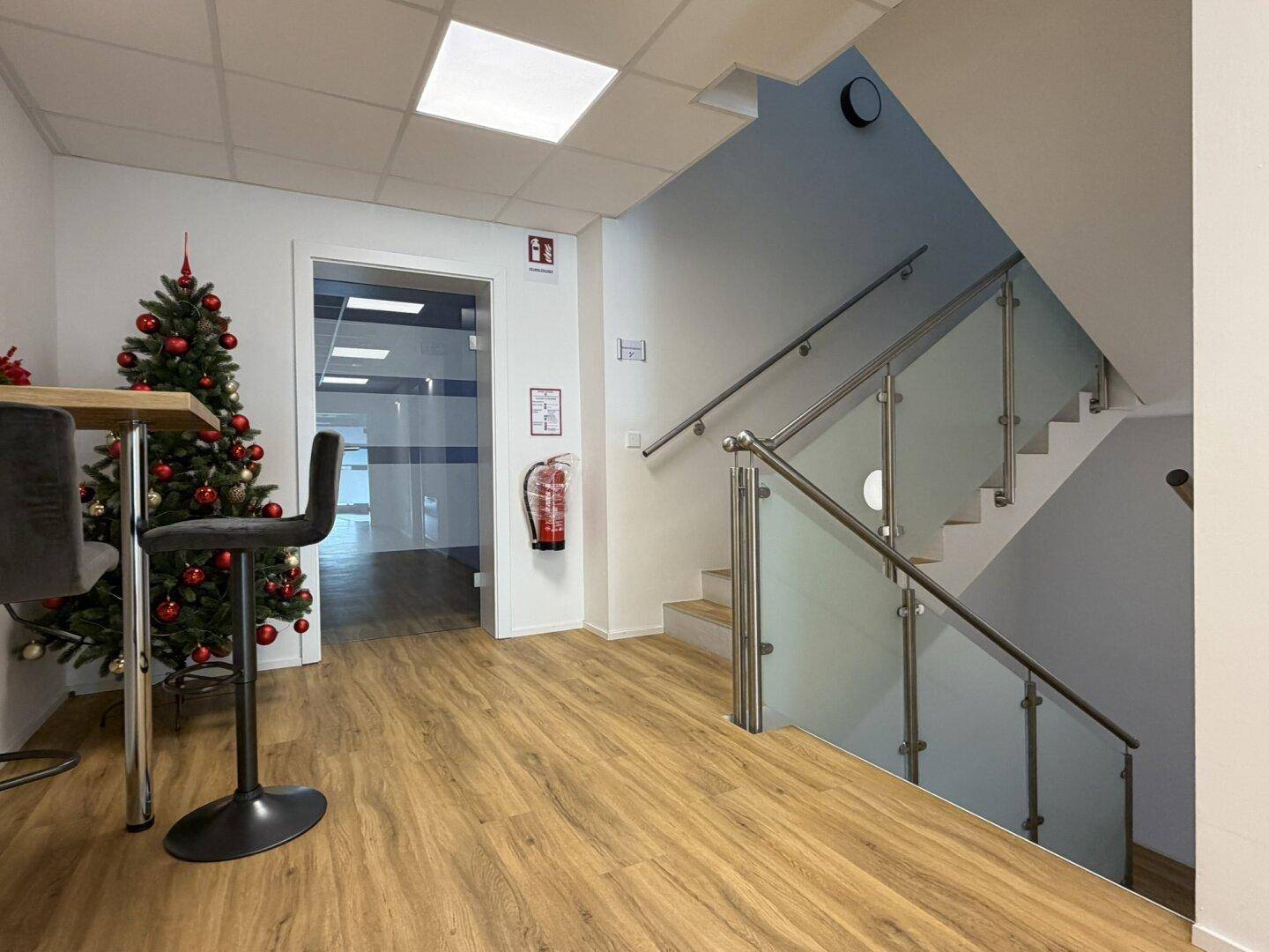Eingangsbereich mit Treppenaufgang, Glasgeländer und festlicher Weihnachtsdekoration.