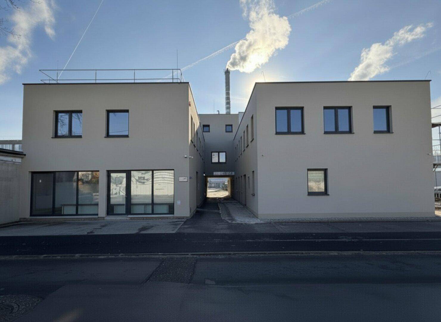 Neubau mit schlichter Fassade, modernen Fenstern und Durchgang zwischen den Gebäudeteilen.