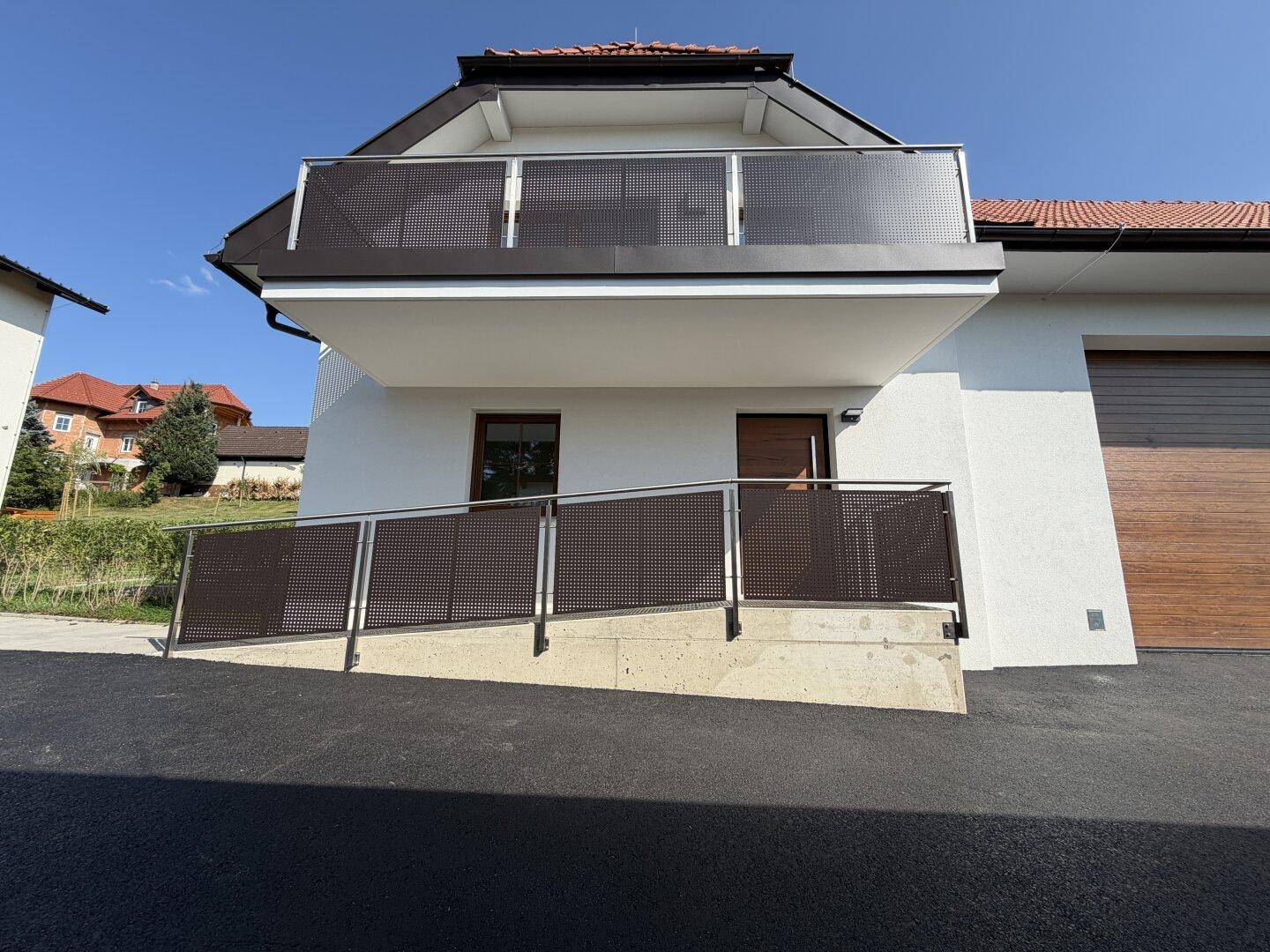 Neubau mit moderner Architektur, barrierefreiem Zugang über eine Rampe und Balkon.