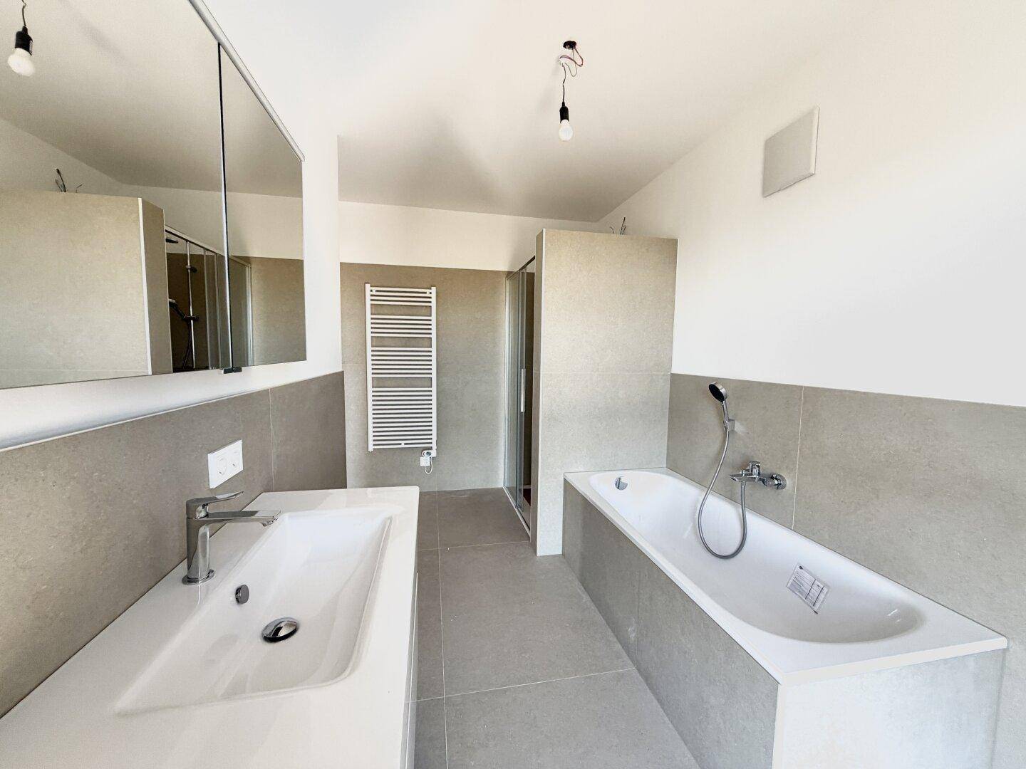 Modernes Badezimmer mit Badewanne, Dusche, Einzelwaschbecken und beheiztem Handtuchhalter.