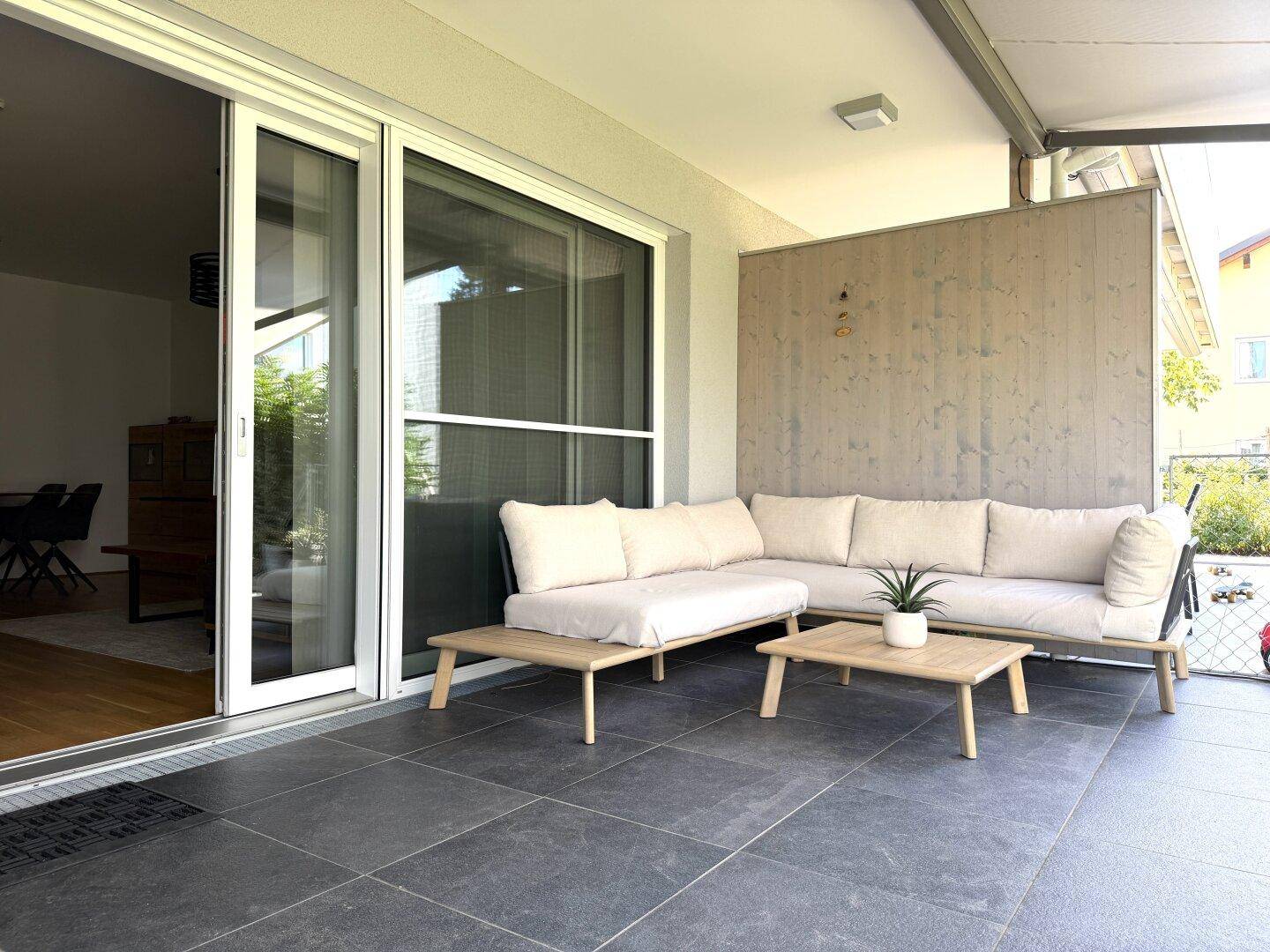 Geräumige Terrasse mit Lounge-Möbeln und Zugang zum Innenbereich durch große Schiebetüren.