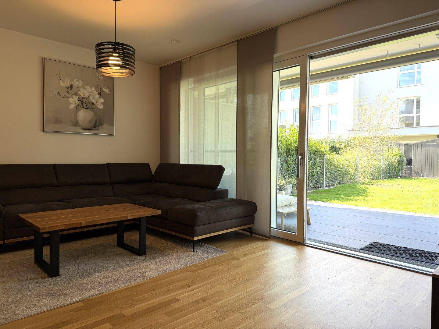 Helles Wohnzimmer mit Holzboden, gemütlichem Sofa und direktem Zugang zur Terrasse und zum Garten.