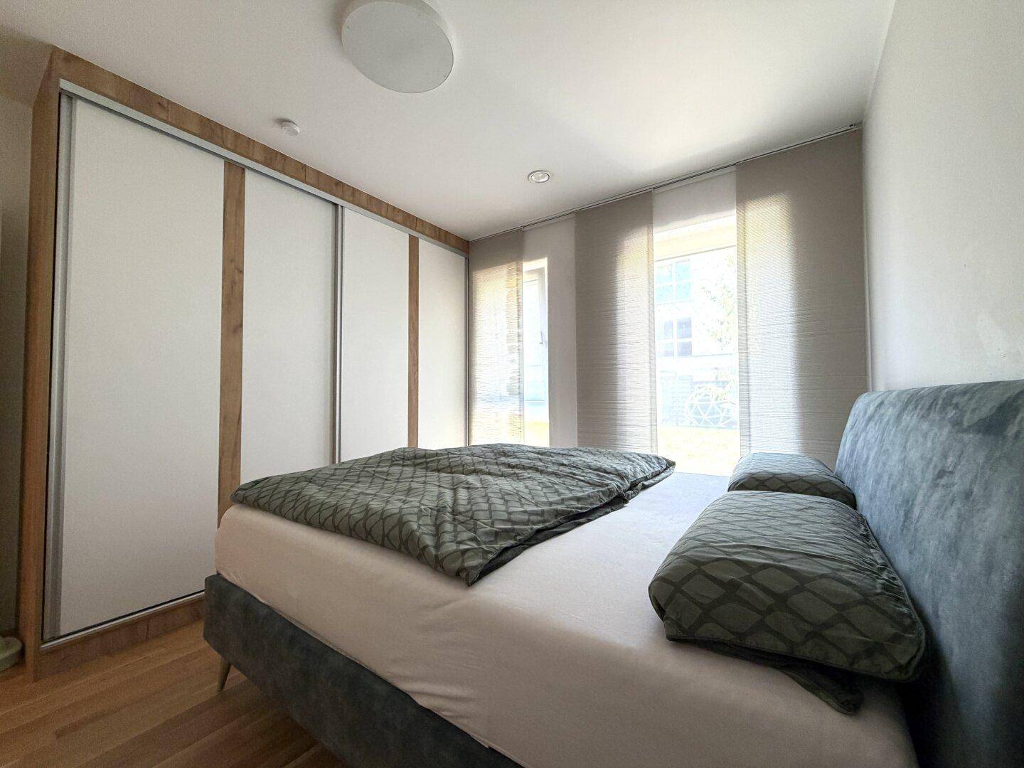 Helles Schlafzimmer mit Holzboden, großem Bett und Einbauschränken entlang einer Wand.