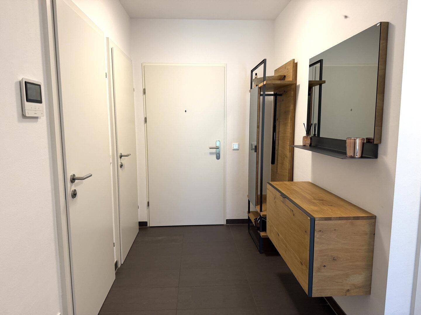 Eingangsbereich mit moderner Garderobe, Spiegel und Holzelementen, bietet praktischen Stauraum.