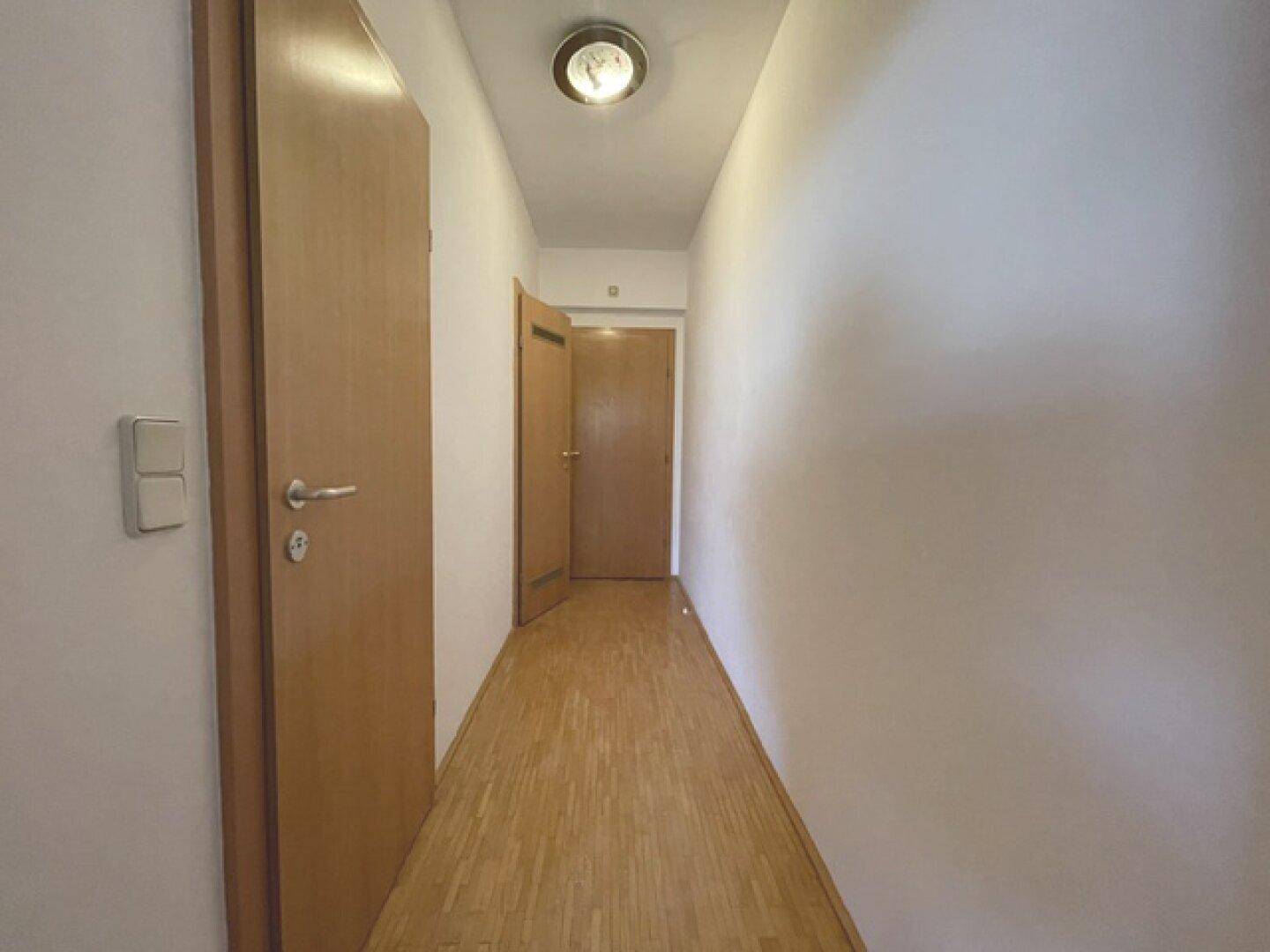 Heller Flur mit Holztüren und Parkettboden, der zu den verschiedenen Räumen der Wohnung führt.