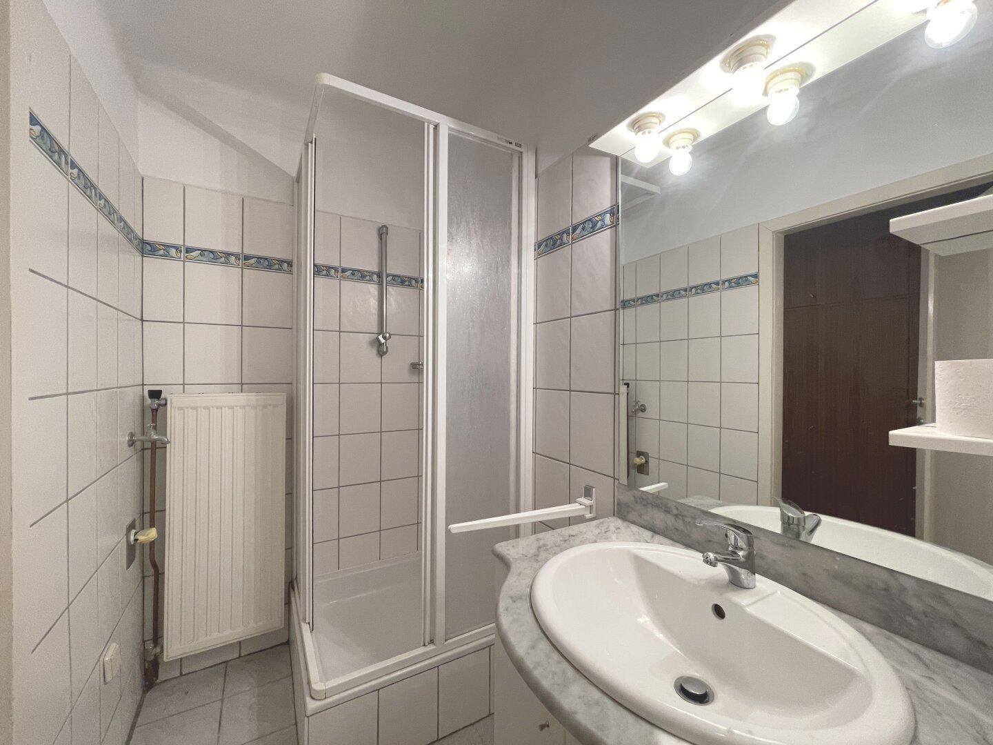 Badezimmer mit Duschkabine, Waschtisch und weiß-blauen Fliesen.
