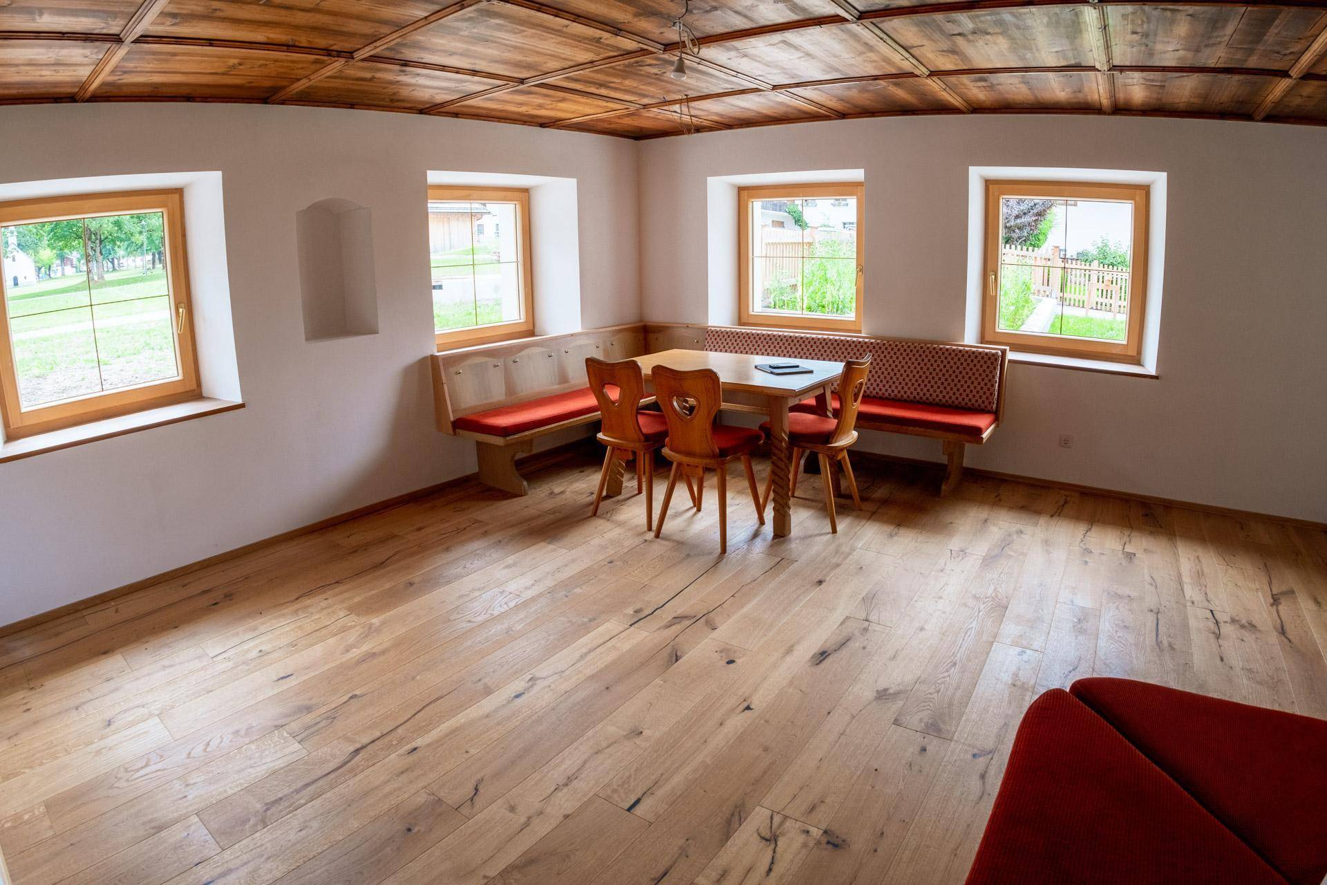 Geräumiger Wohn-Essbereich mit Holzboden, Holzkassettendecke und gemütlicher Eckbank am Fenster.