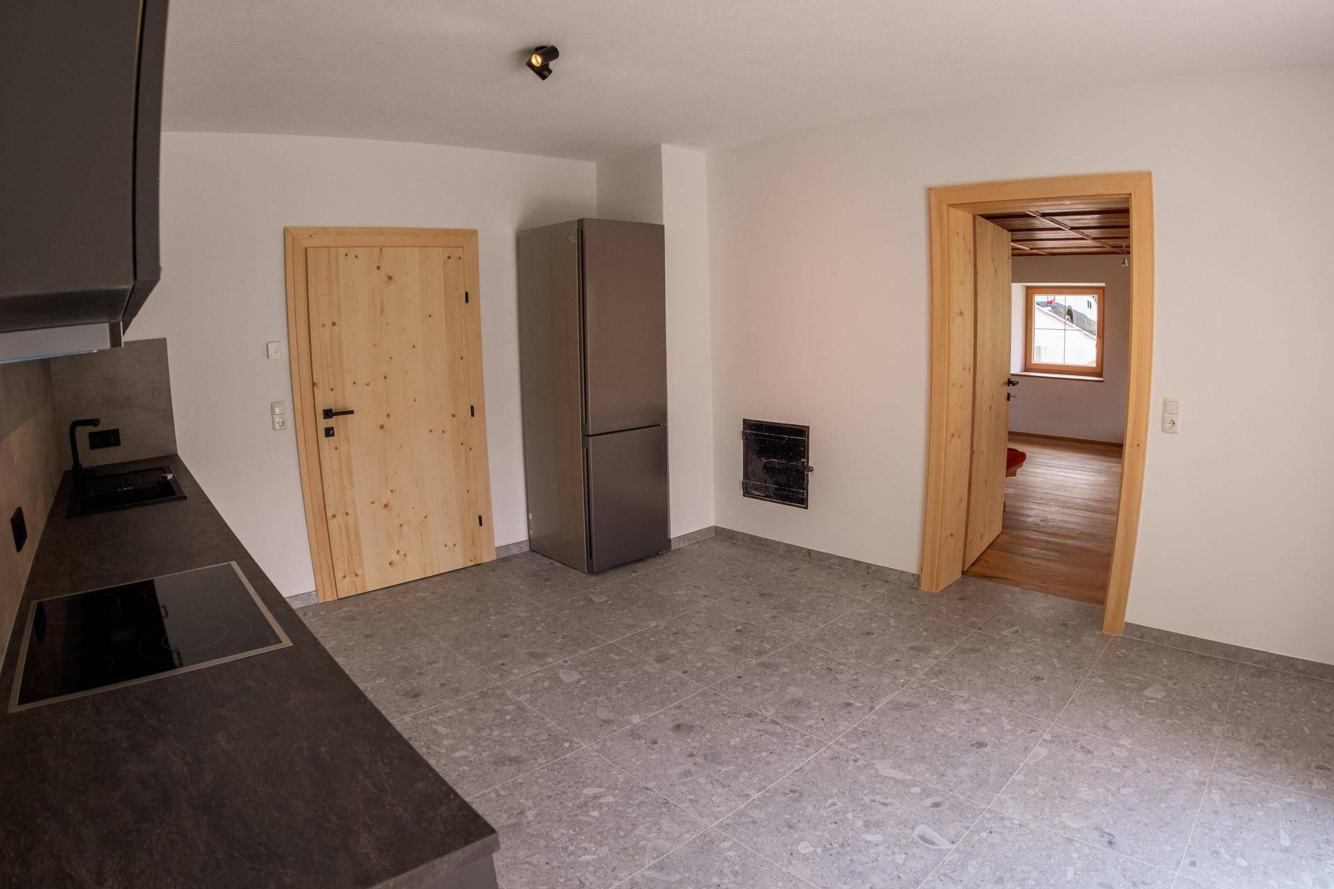 Moderne Küche mit dunkler Arbeitsplatte, integriertem Kochfeld und großem Kühlschrank.