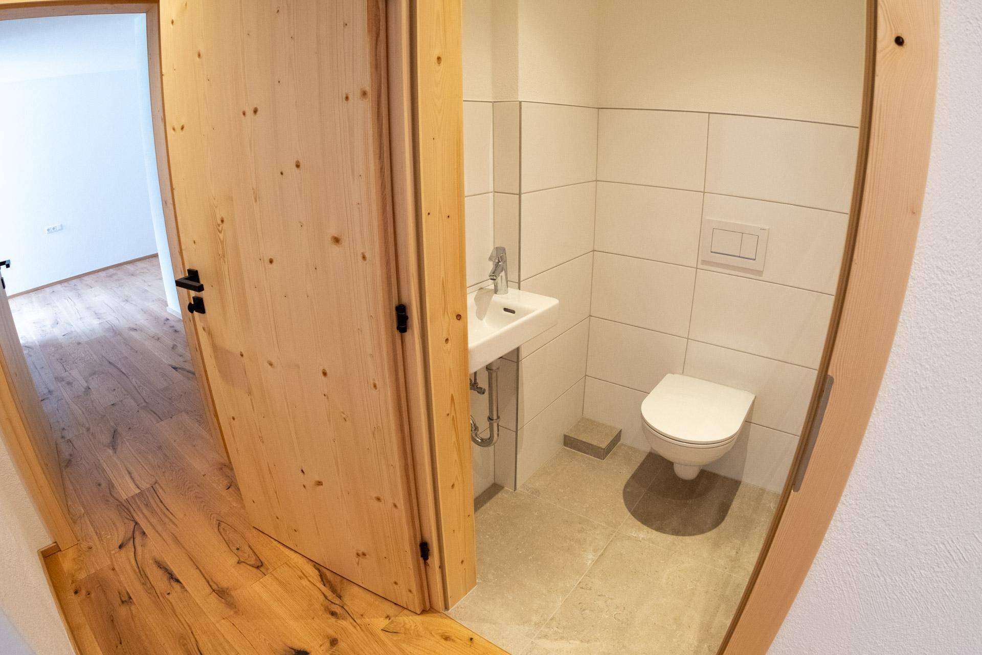 Kleines Gäste-WC mit Waschbecken, Toilette und hellen Fliesen.