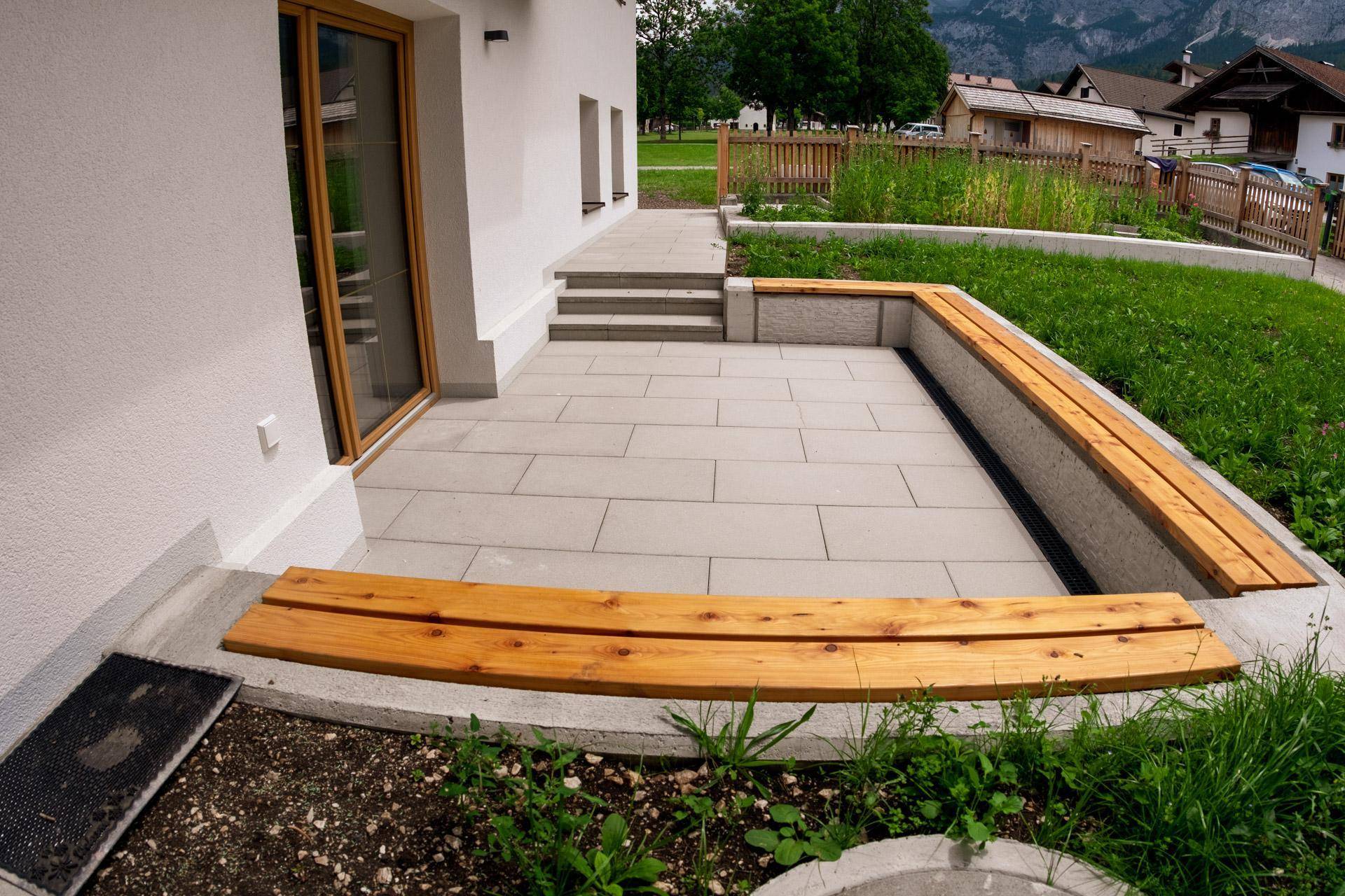 Gepflegte Terrasse mit integrierten Holzbänken und Blick auf die umliegende Natur und Berge.