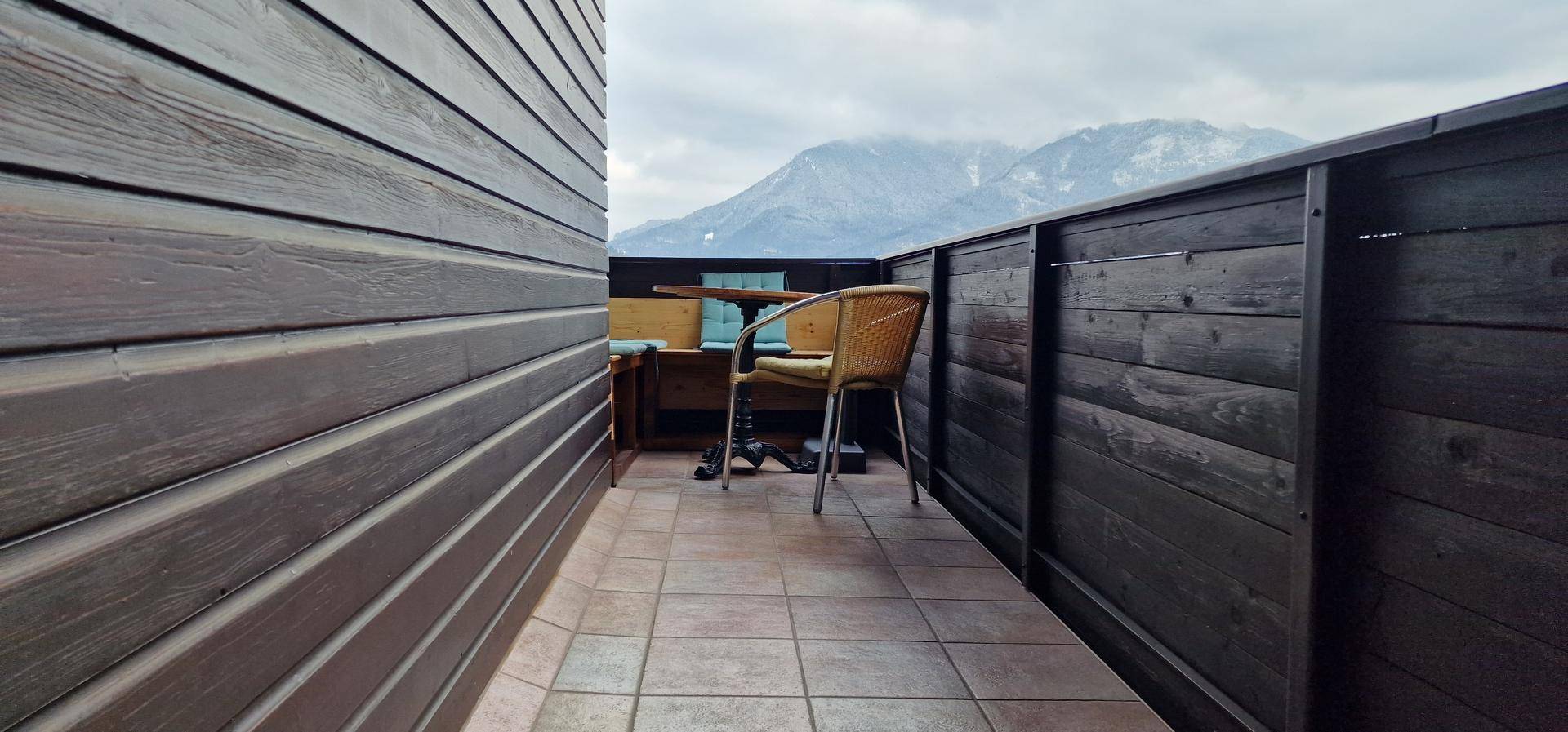 Balkon mit Fliesenboden und Holzwänden, bietet einen weiten Blick auf die umliegende Berglandschaft.