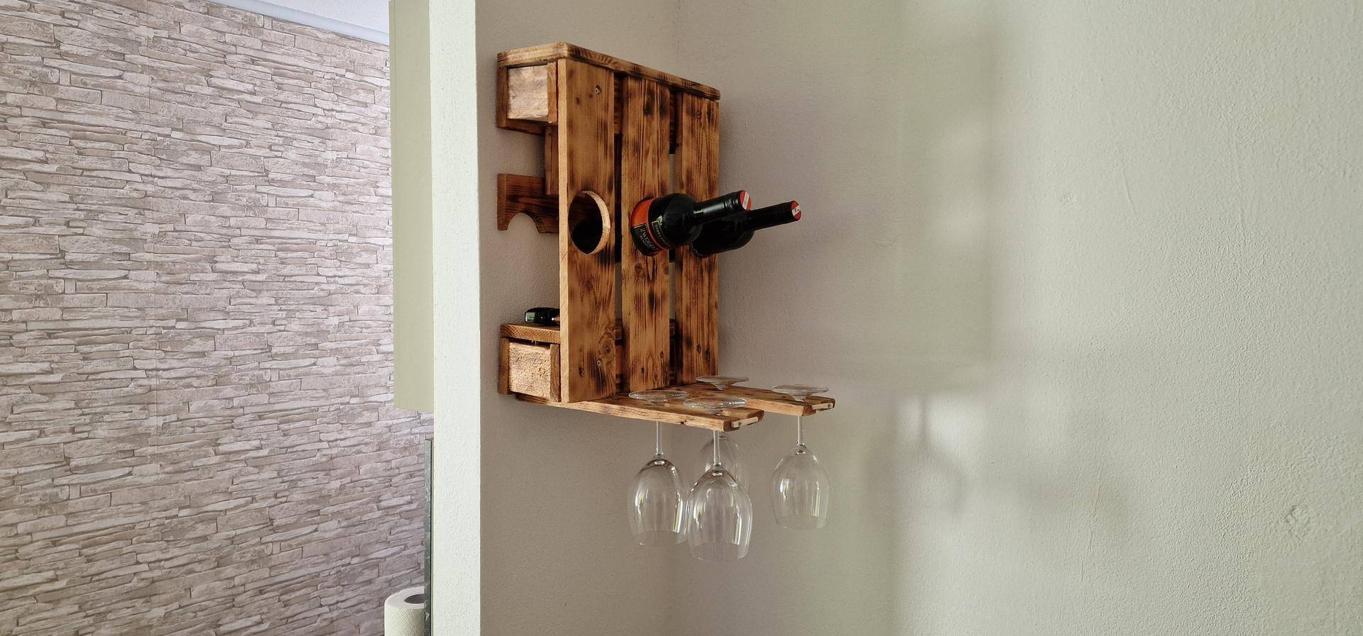 Rustikales Weinregal aus Holz mit Flaschen und Gläsern, als dekoratives Element an der Wand.