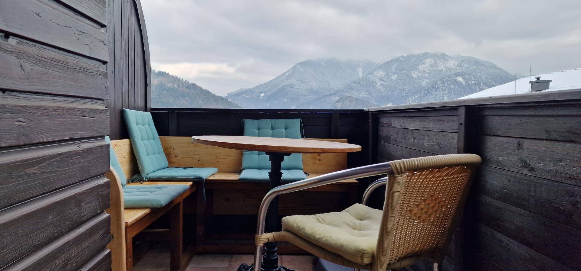 Gemütlicher Balkon mit Sitzgelegenheiten und atemberaubendem Blick auf schneebedeckte Berge.