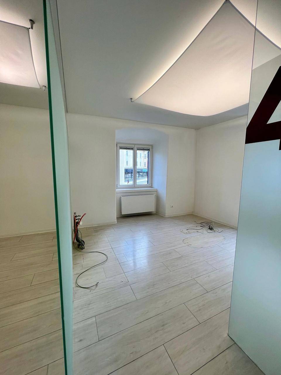 Helles Büro mit einem Fenster, das Tageslicht hereinlässt, und modernen Deckenleuchten.