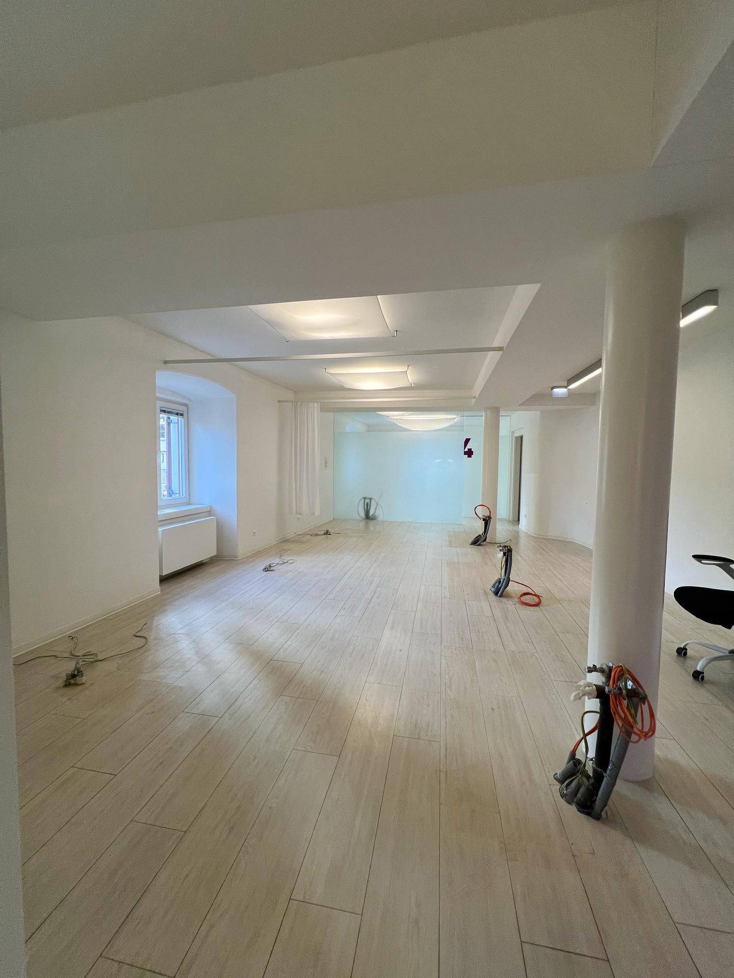 Geräumiger, leerer Büroraum mit hellen Fliesenböden, weißen Wänden und modernen Deckenleuchten.