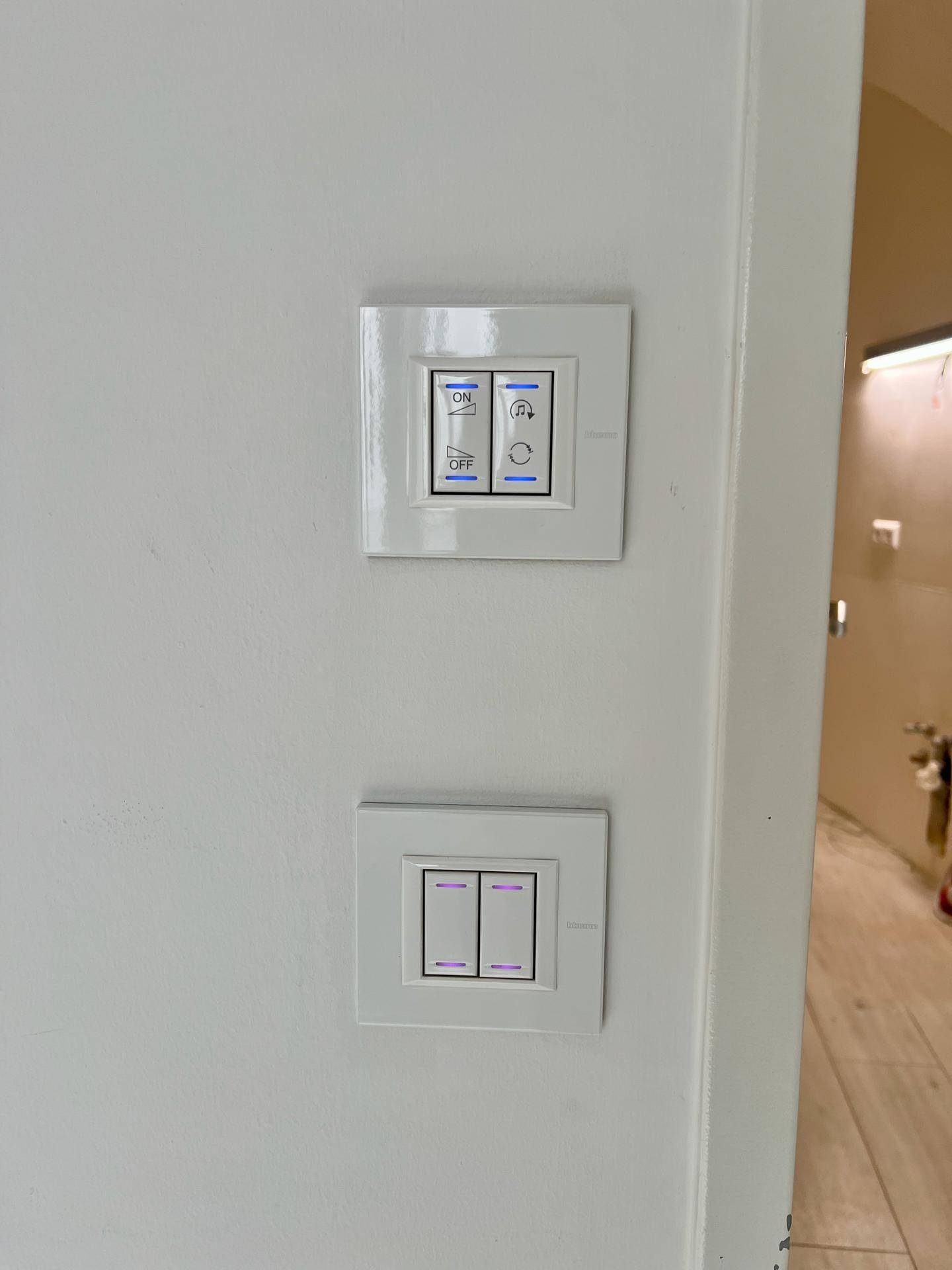 Moderne Lichtschalter an einer weißen Wand mit blauen und lila LED-Anzeigen.