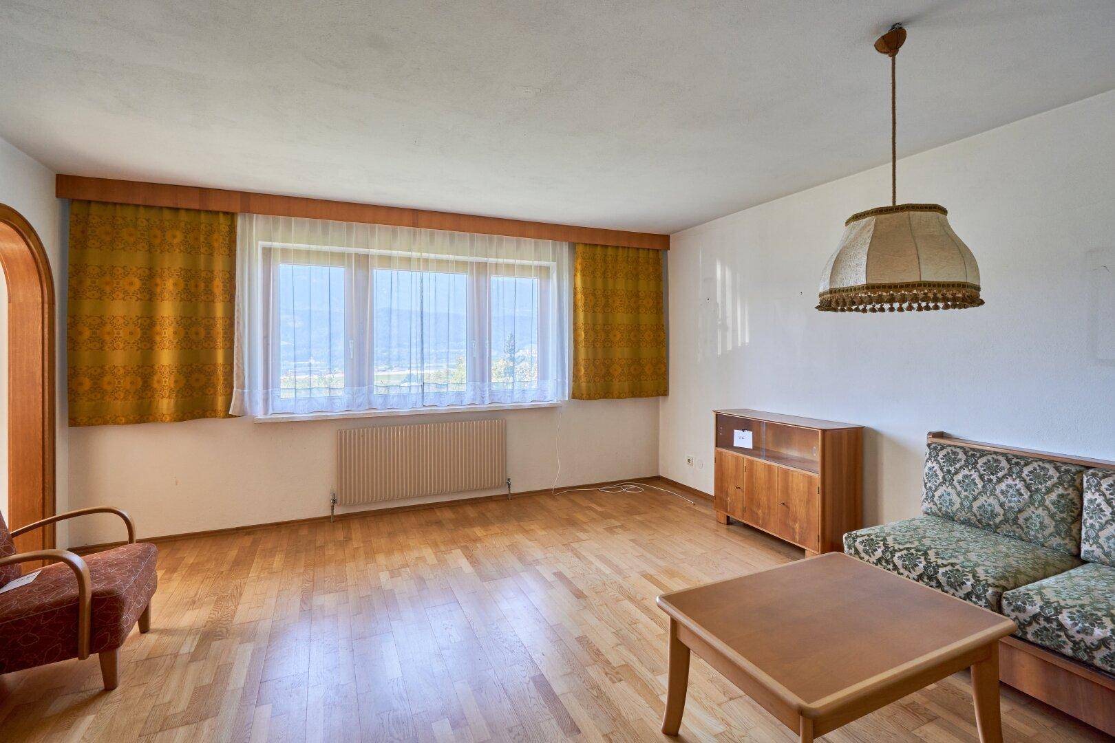 Helles Wohnzimmer mit Parkettboden, einem Fenster mit Bergblick und Vintage-Möbeln in gutem Zustand.