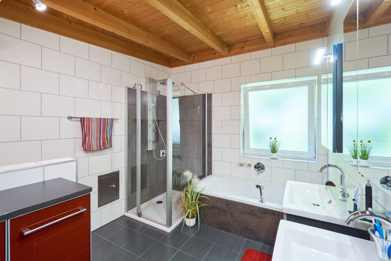 Modernes Badezimmer mit Duschkabine, Badewanne, Doppelwaschbecken und Holzdecke.