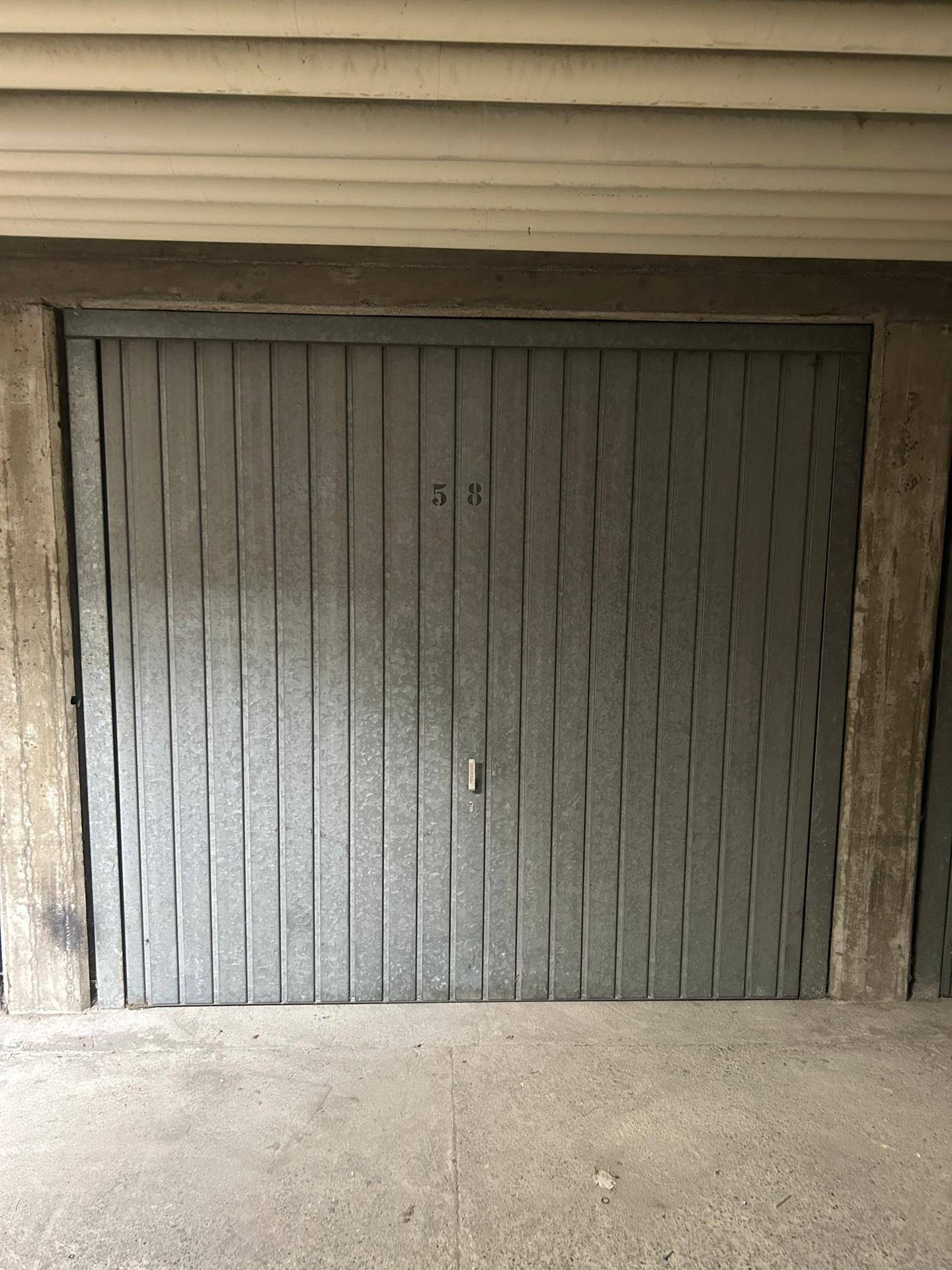 Geschlossene Garagentür mit der Nummer 58 in einer Tiefgarage.