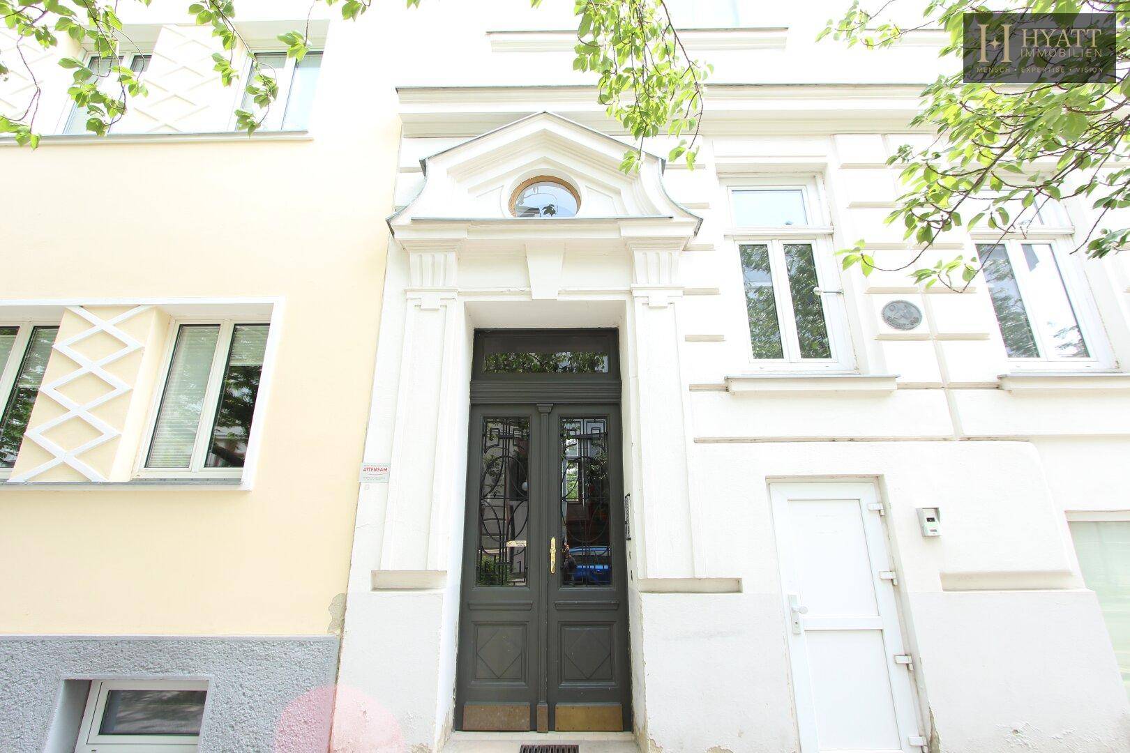 Repräsentativer Hauseingang mit Doppeltür und dekorativen Elementen an der Fassade.